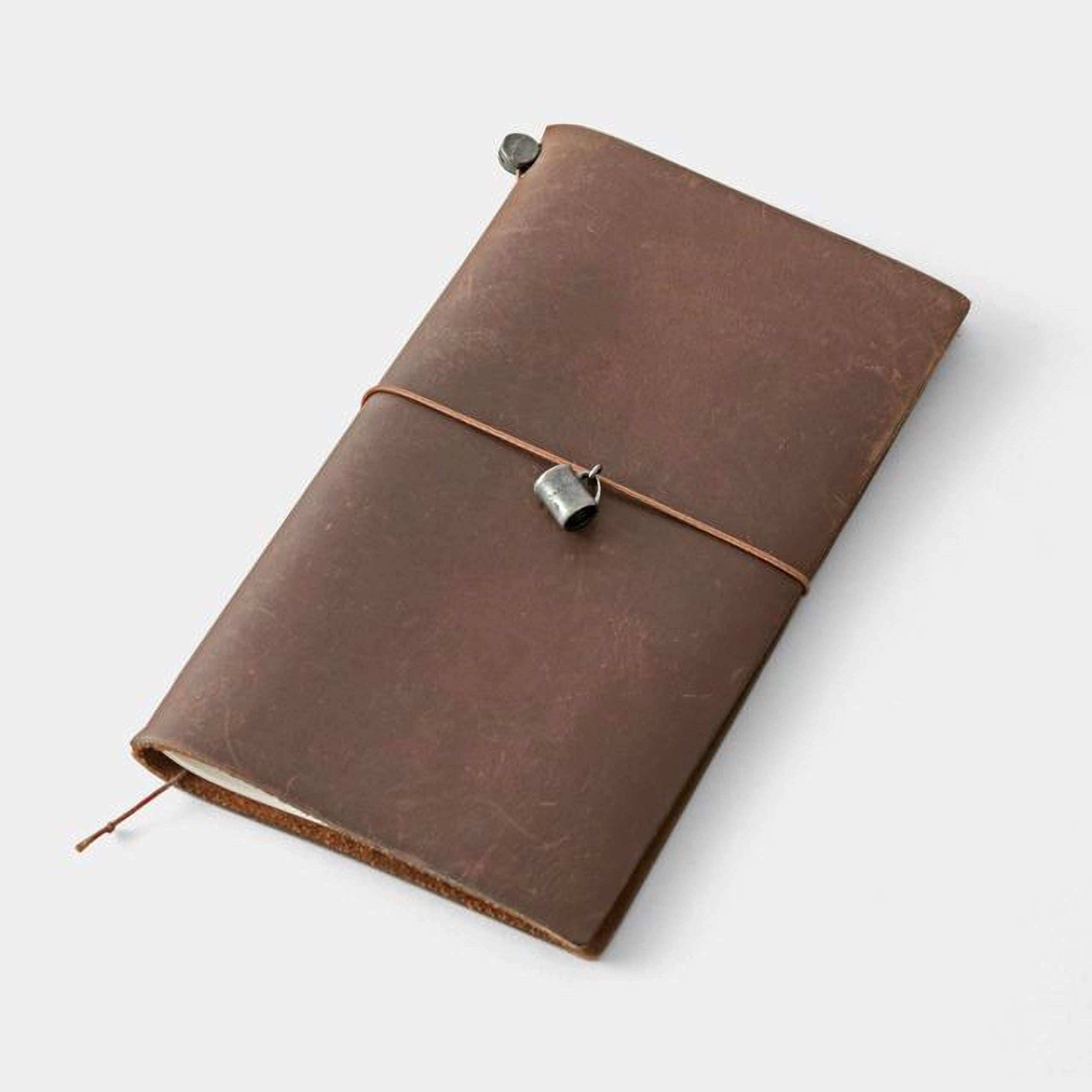 A brown leather-bound notebook with a metal clasp and a leather strap, resting on a white surface.