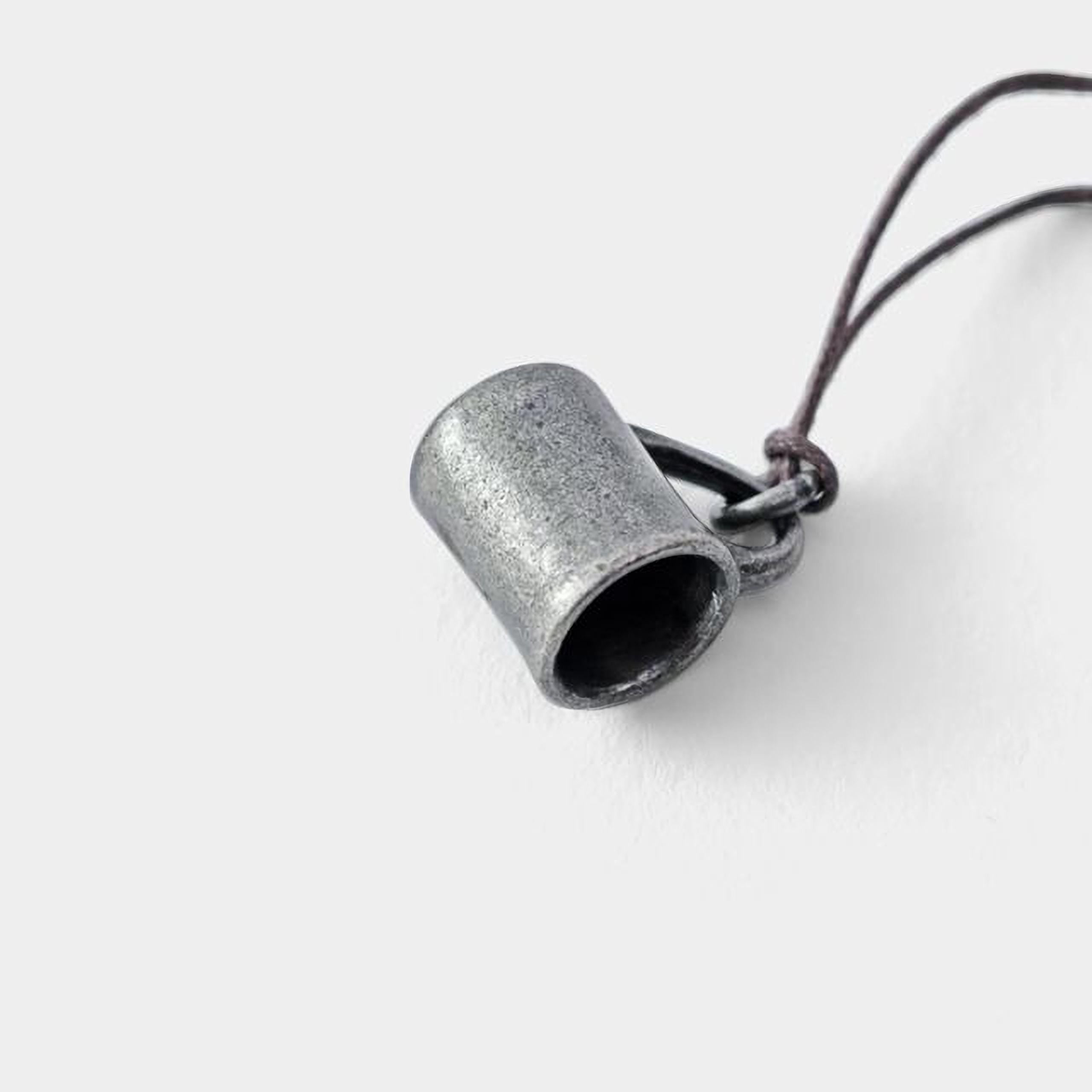A silver-colored metal object, possibly a pendant or charm, is shown against a plain white background.