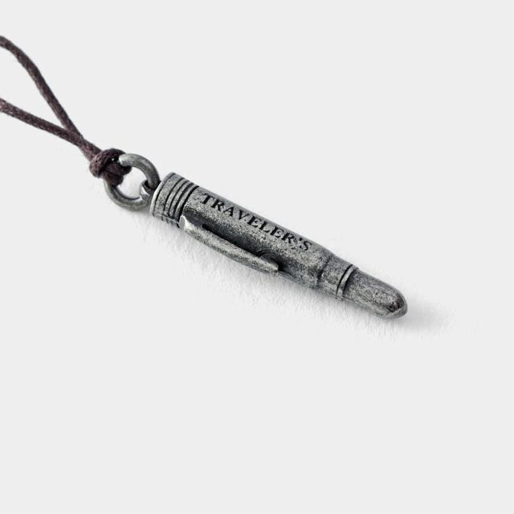 A silver bullet-shaped pendant with the word "TRAVELERS" engraved on it.