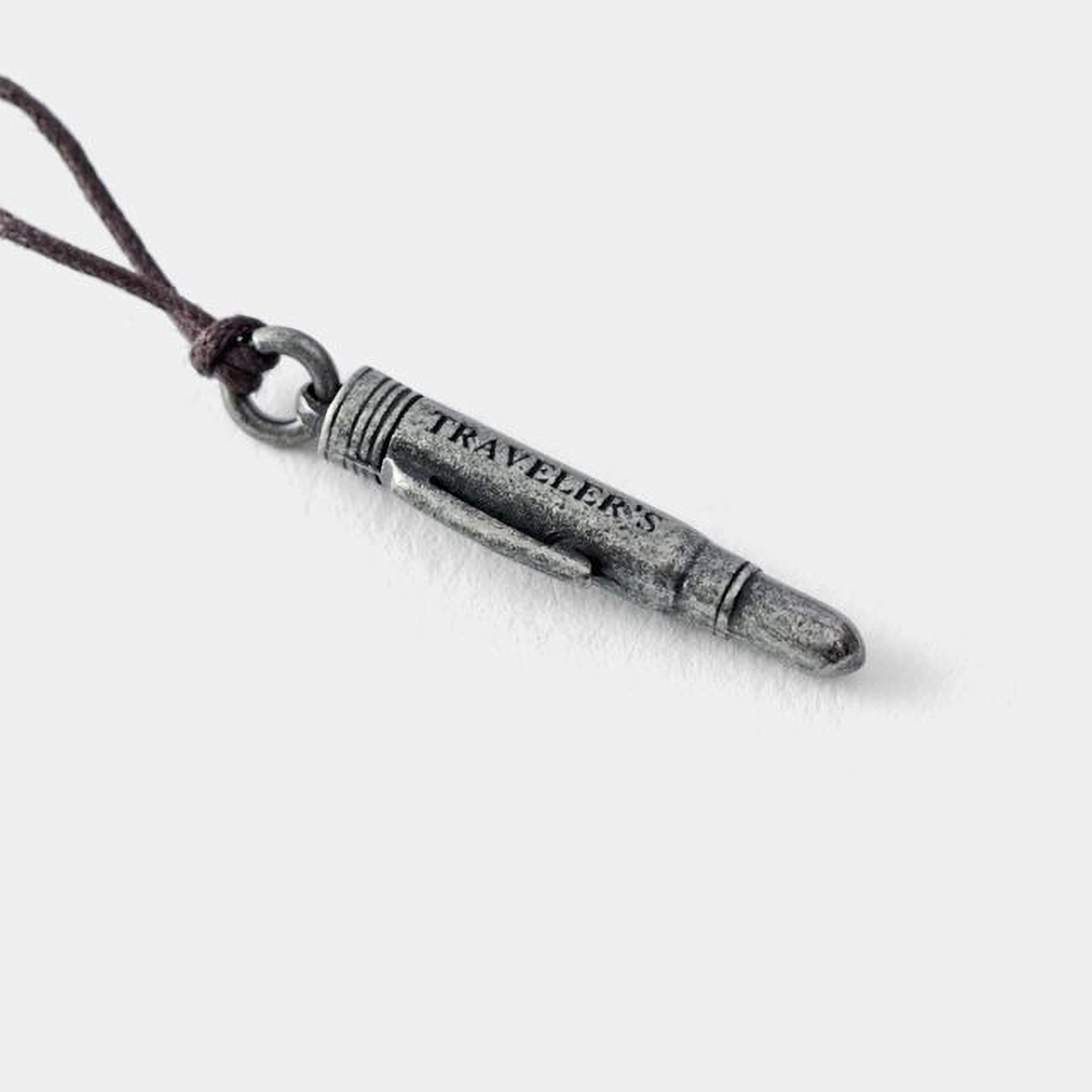 A silver bullet-shaped pendant with the word "TRAVELERS" engraved on it.