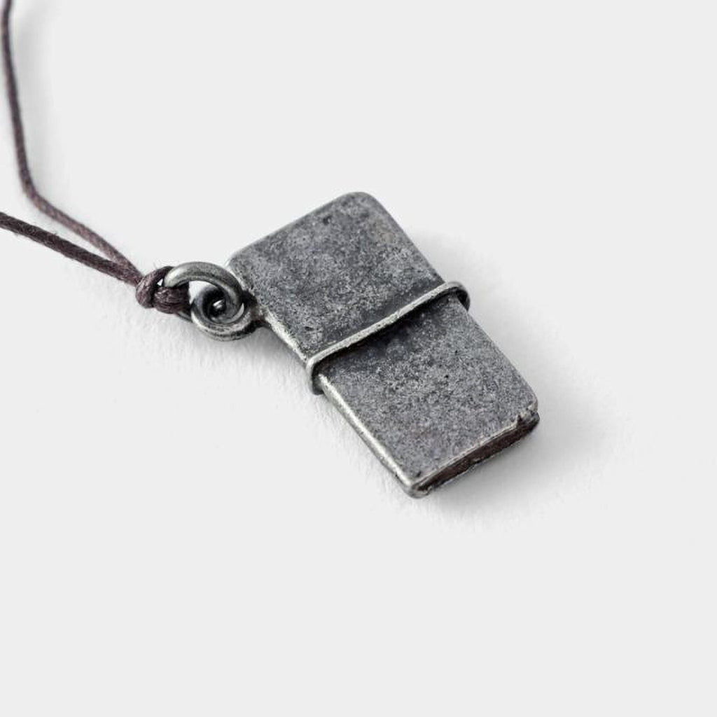 A small, rectangular metal pendant with a leather cord attached to it.