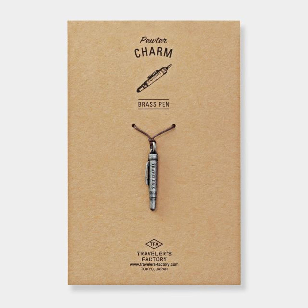 a brass pen charm attached to a brown paper background.