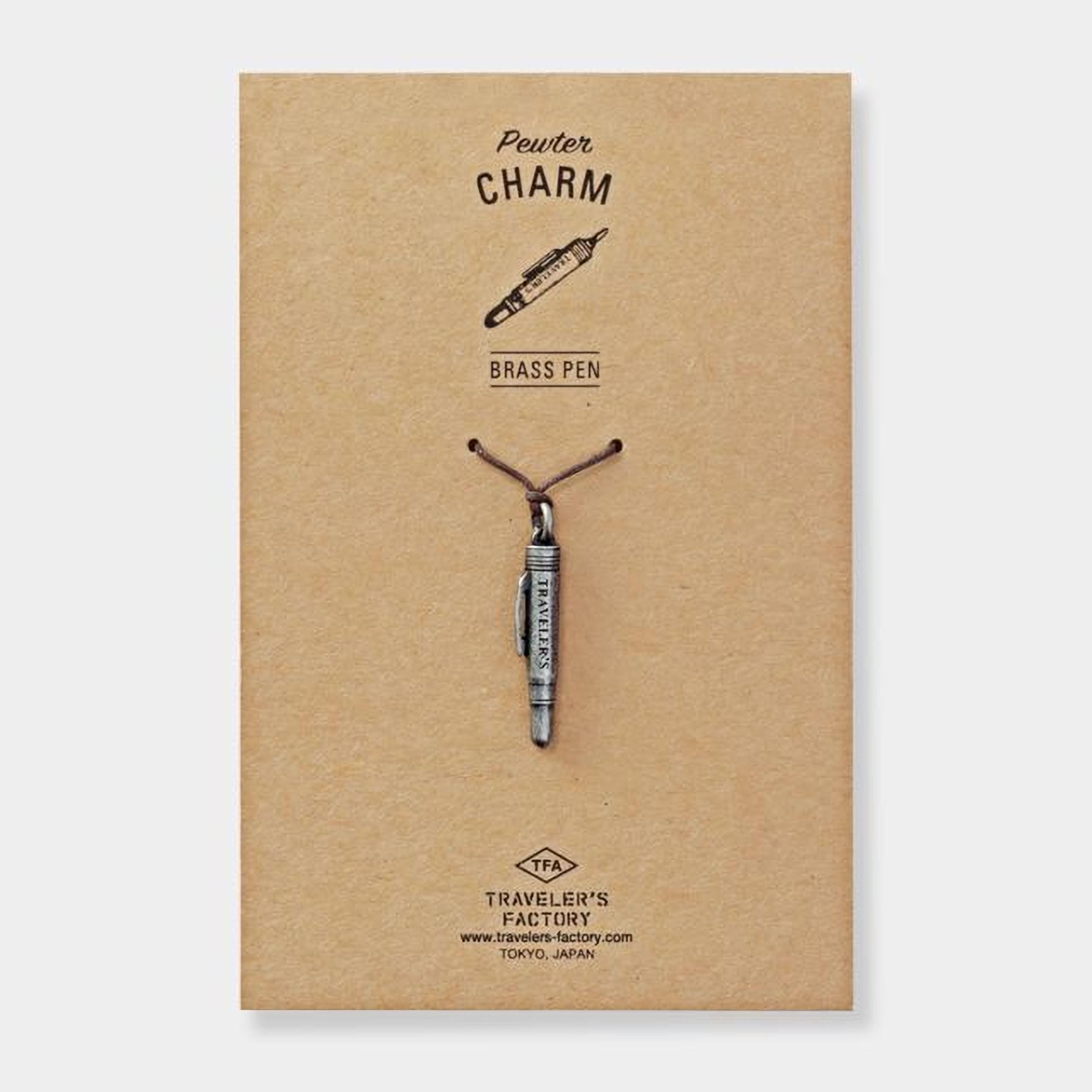 a brass pen charm attached to a brown paper background.