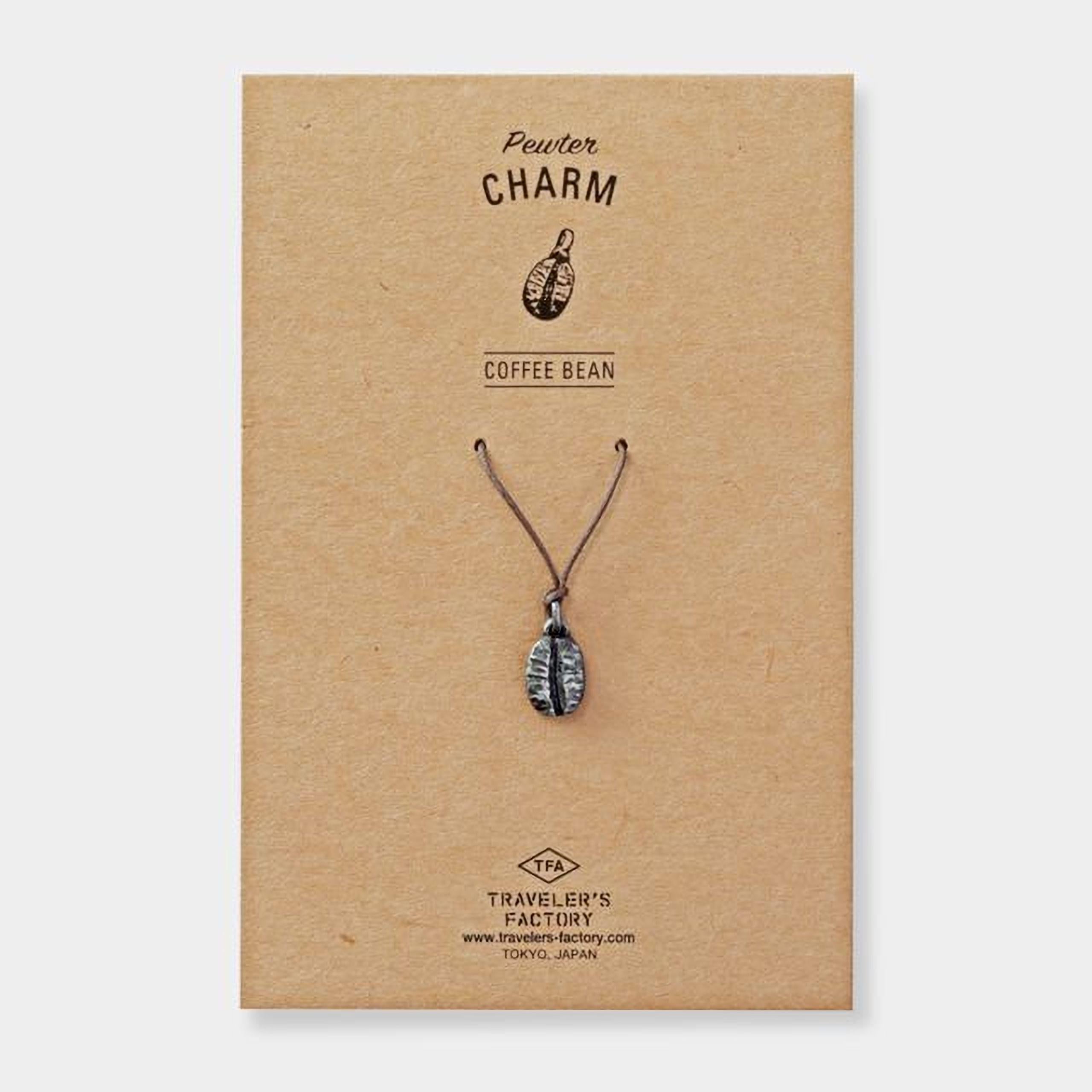 a pendant necklace with a coffee bean pendant, presented on a brown cardboard background.