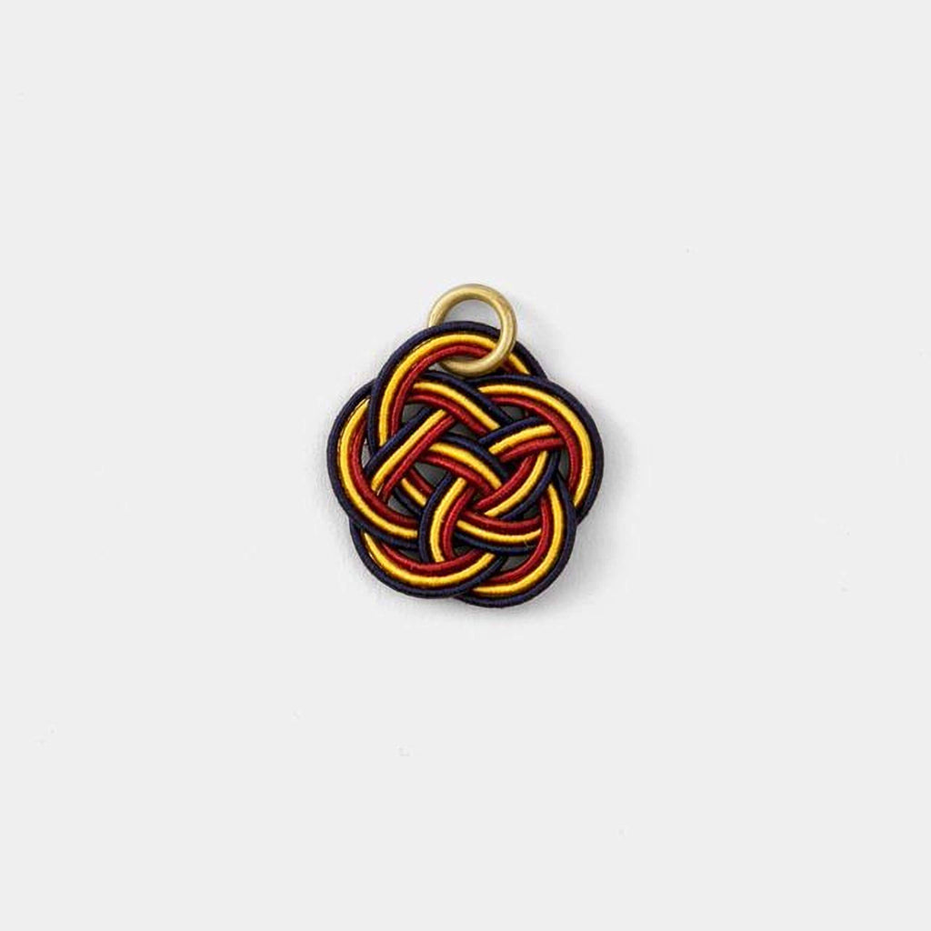 A colorful, braided piece of string or thread with a gold ring attached to it.