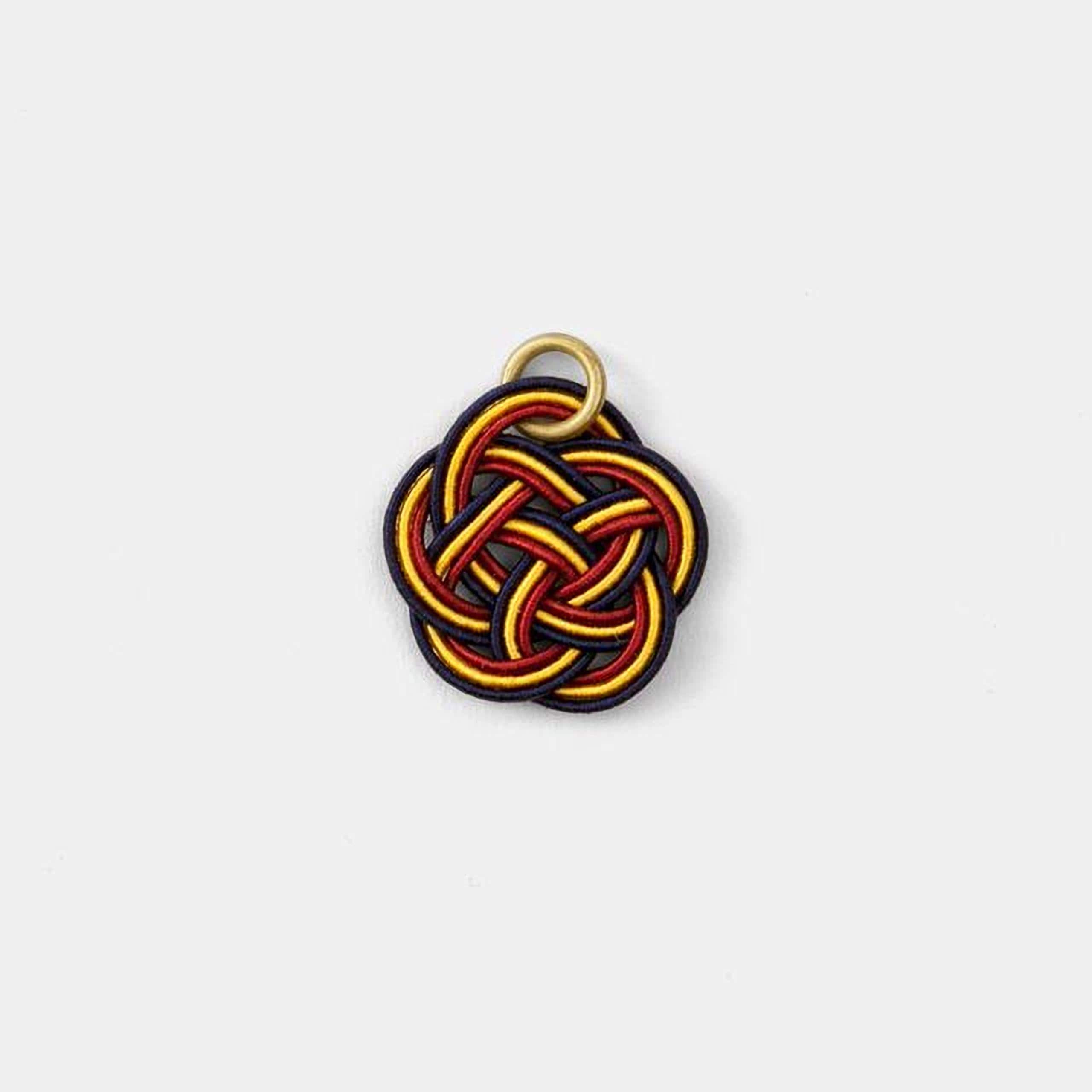 A colorful, braided piece of string or thread with a gold ring attached to it.