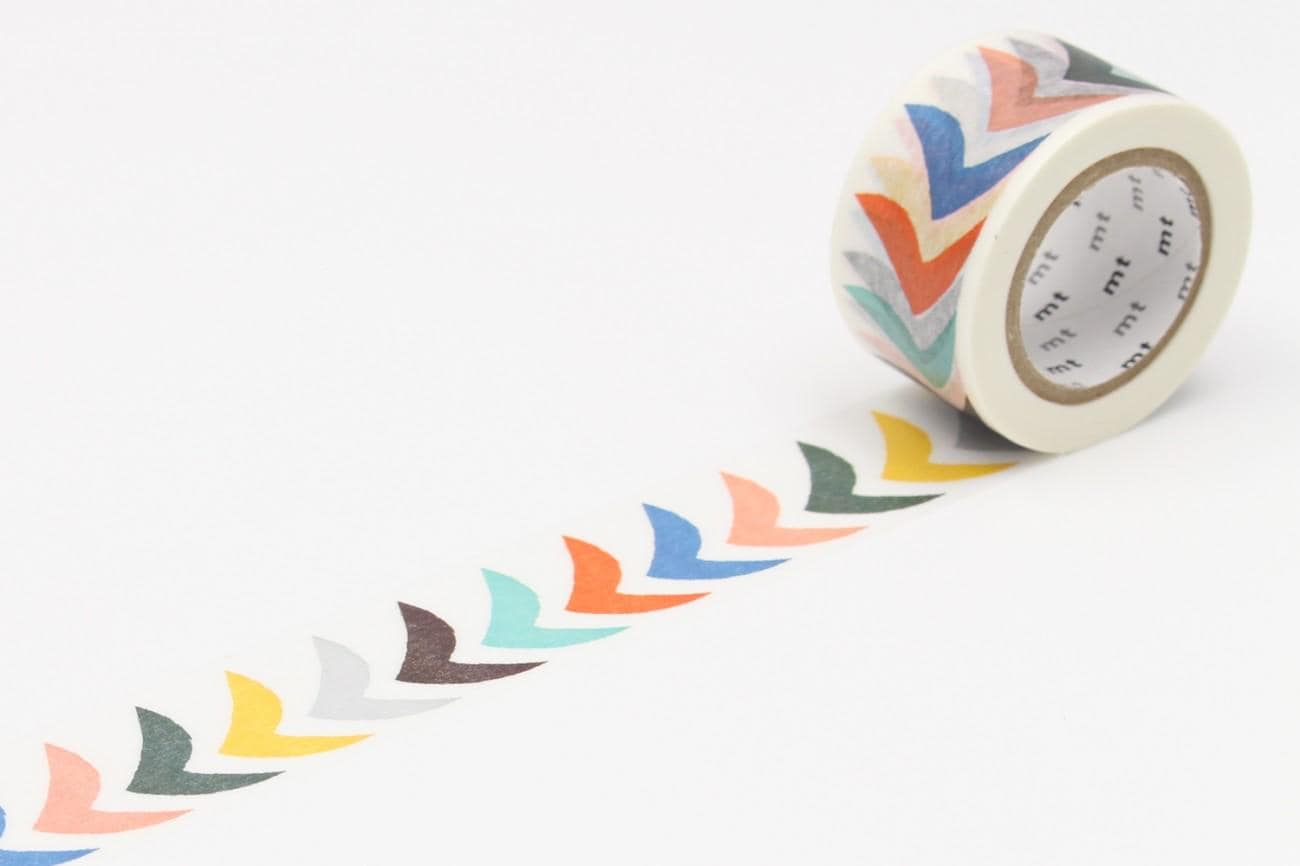 A roll of colorful patterned tape is lying on a white surface, with a row of colorful arrow shapes drawn on it.