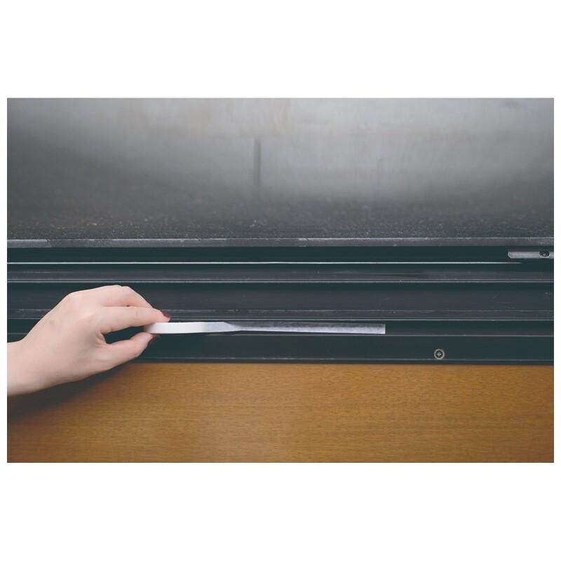 A hand is holding a small object, possibly a tool, and placing it on a black surface.