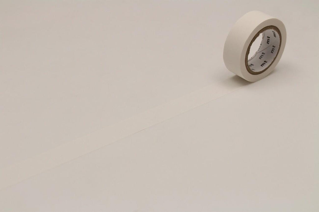 A roll of white masking tape is lying on a plain white surface.