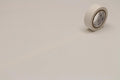 A roll of white masking tape is lying on a plain white surface.