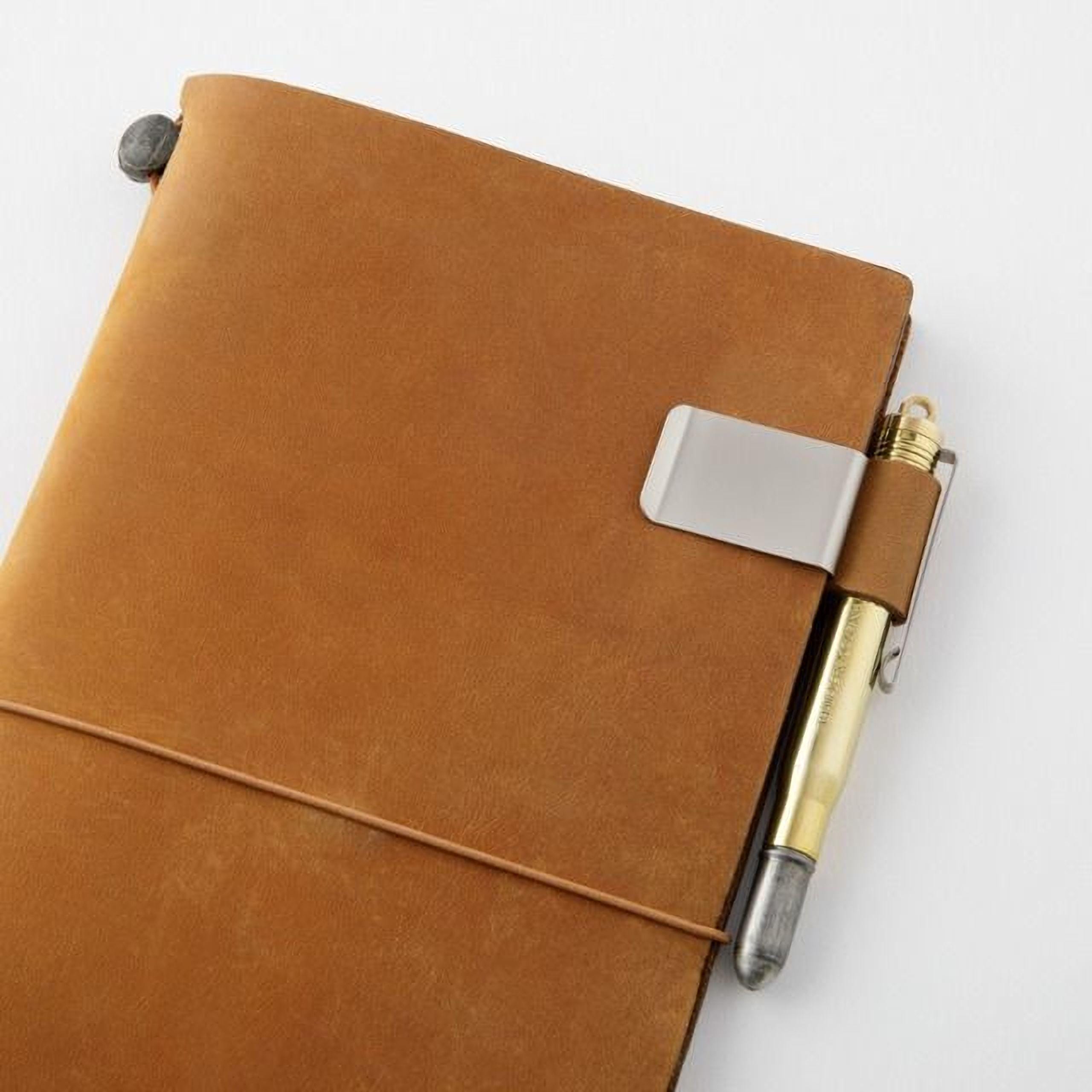 A brown leather-bound notebook with a pen clip attached to the top right corner.