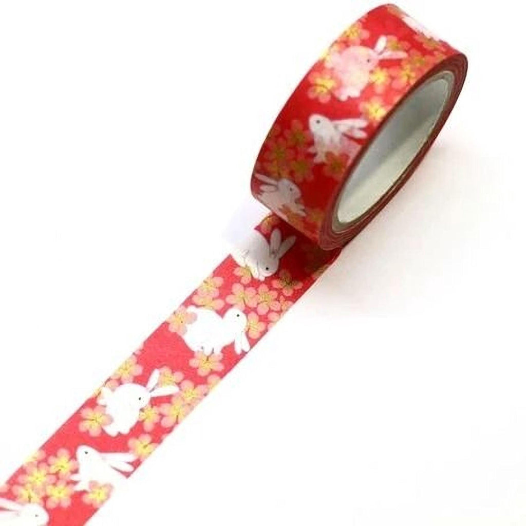 A roll of red and gold washi tape with a pattern of white rabbits on a red background.