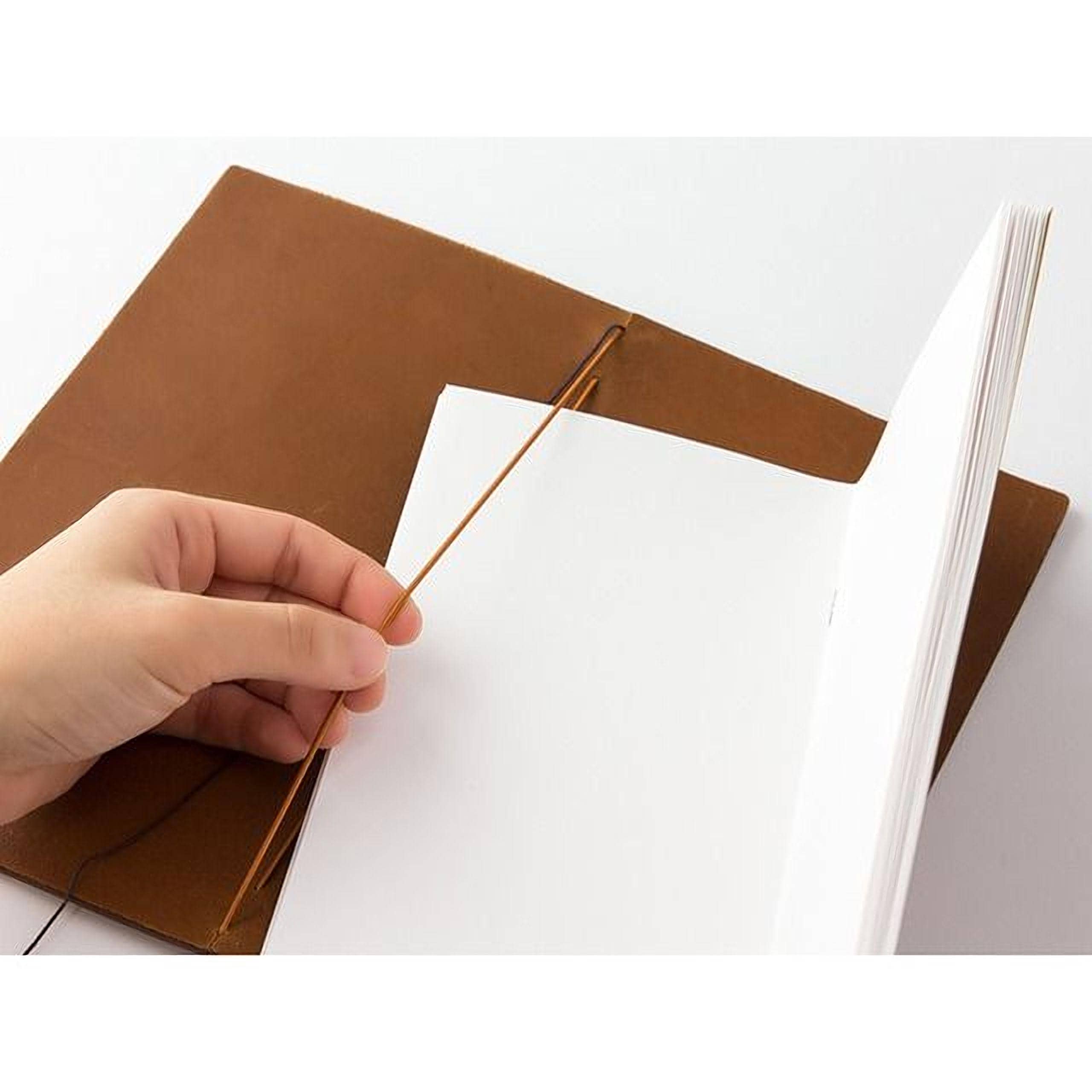 A hand is holding a brown leather-like object, which appears to be a page from a book or a notebook.