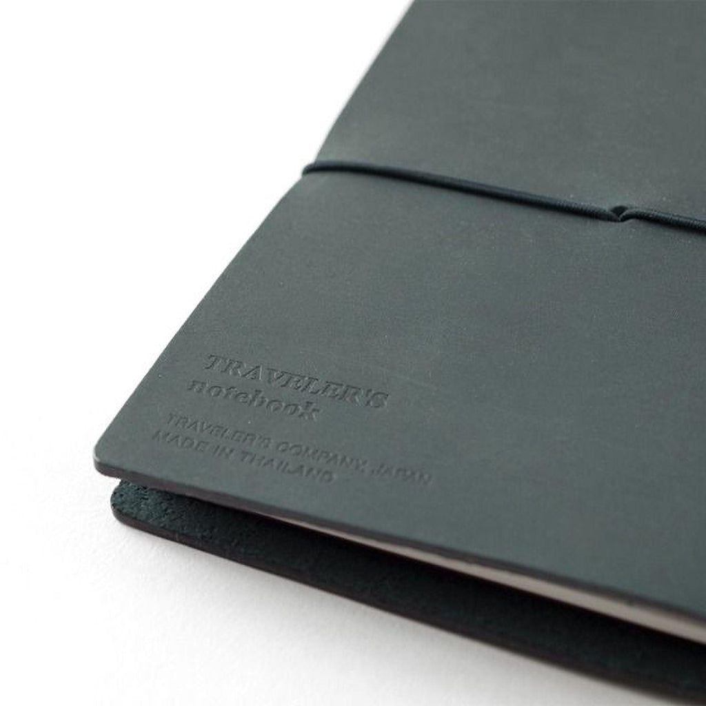 A close-up view of a black leather-bound notebook with embossed text on the cover.