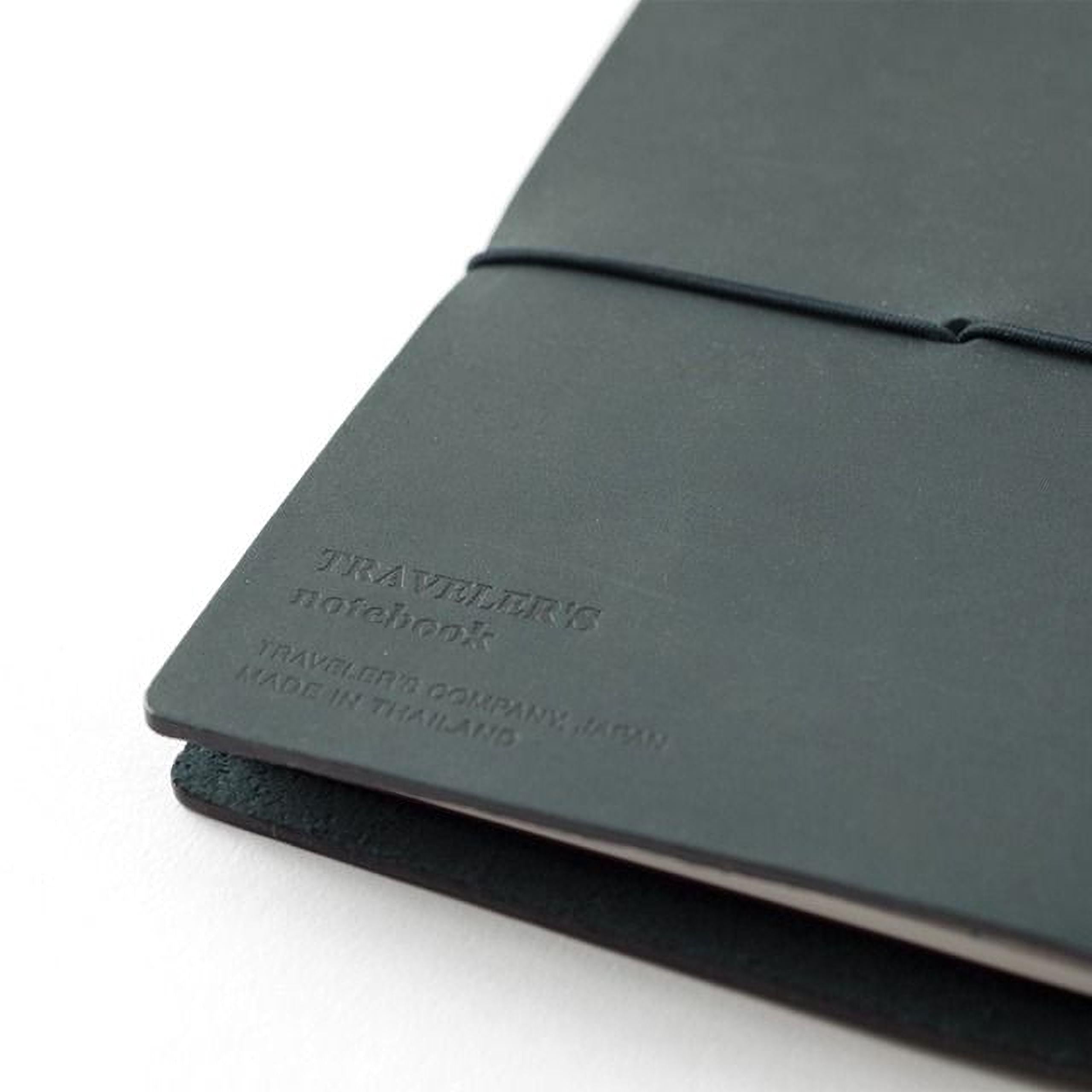A close-up view of a black leather-bound notebook with embossed text on the cover.