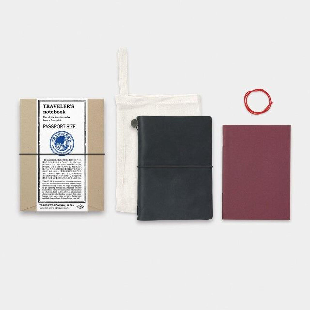 a variety of travel-related items, including a passport-sized notebook, a black leather-bound notebook, a red string, and a maroon notebook.