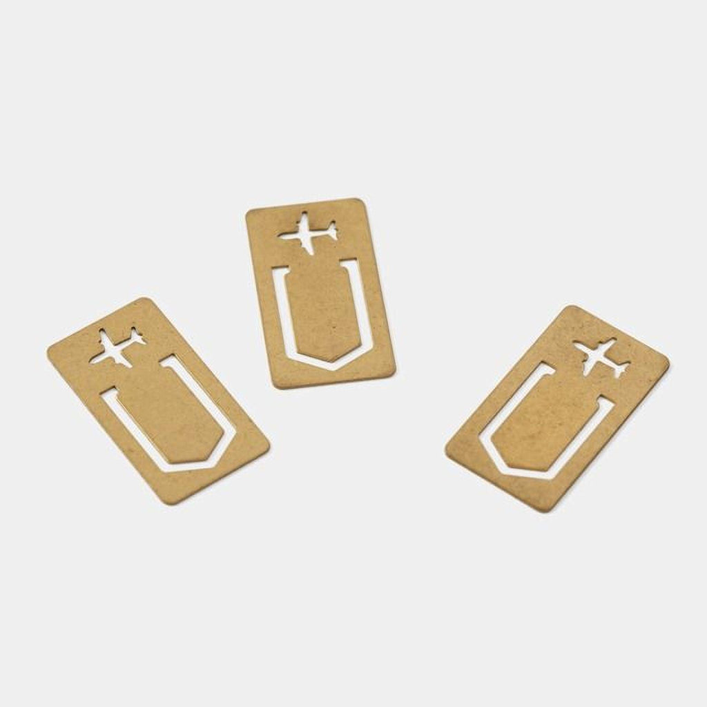 Three gold-colored metal bookmarks with airplane cutouts are arranged on a white background.