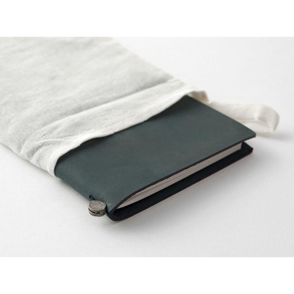A black notebook with a white cloth wrapped around it, placed on a white surface.