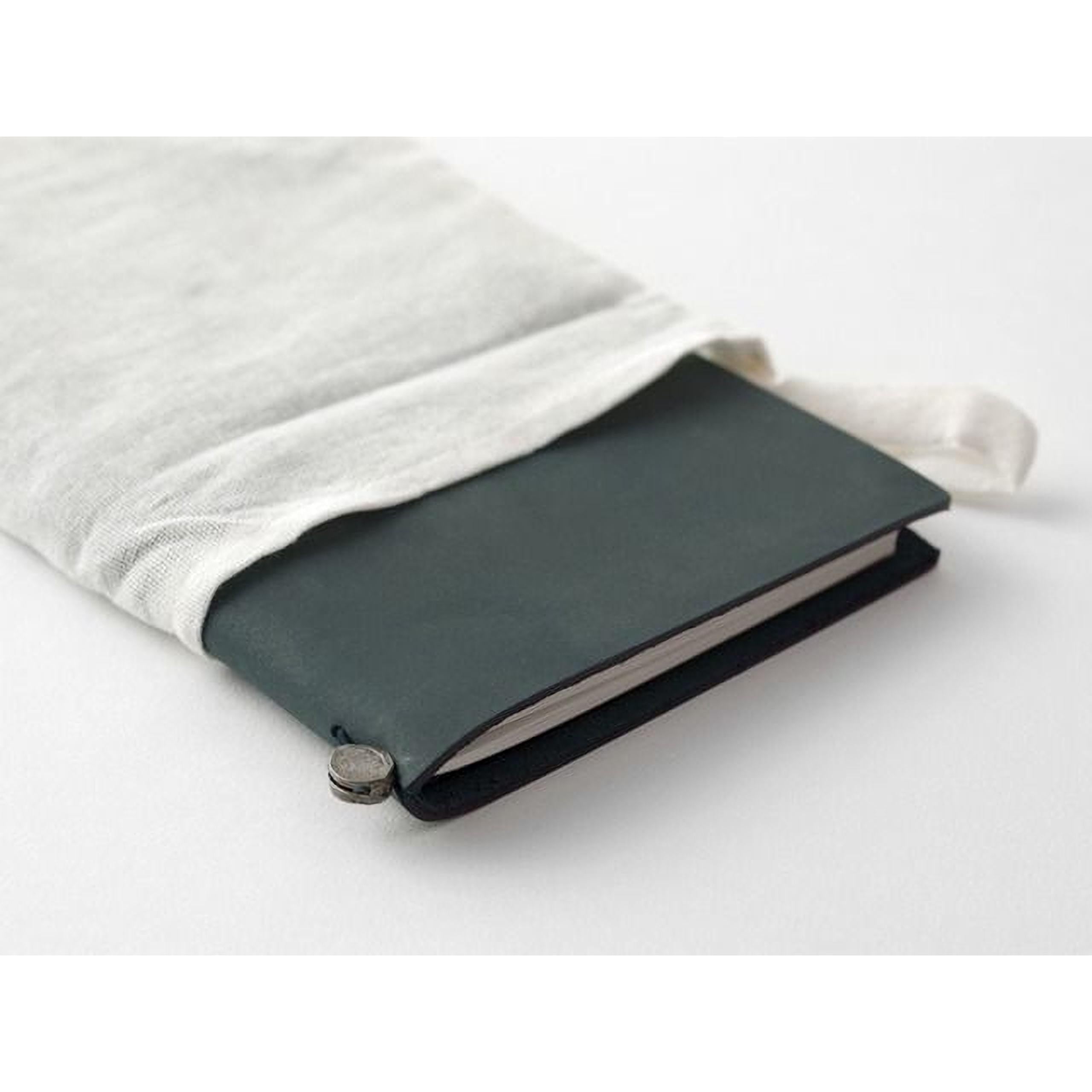 A black notebook with a white cloth wrapped around it, placed on a white surface.