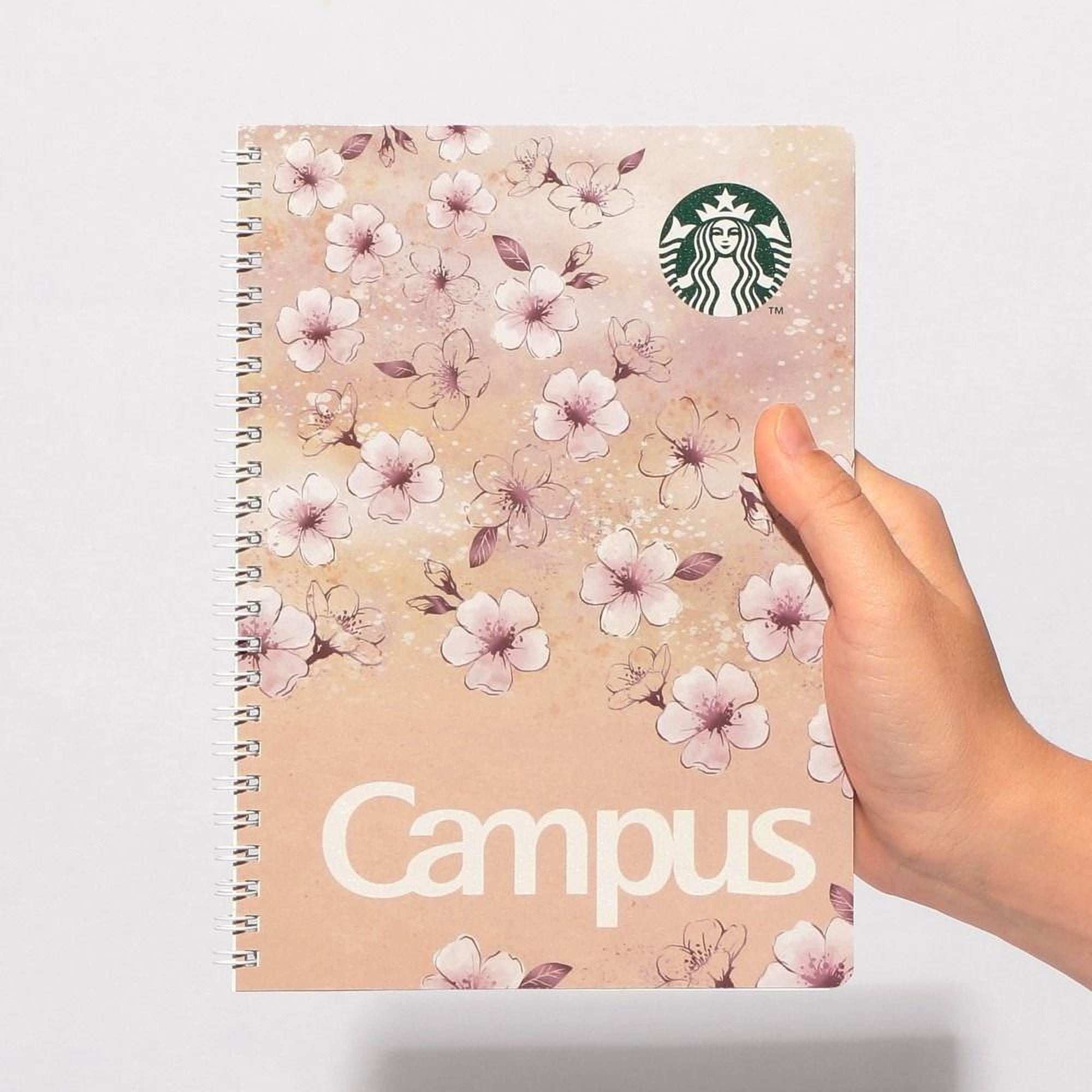 A hand is holding a notebook with a floral design and the word "Campus" printed on it.