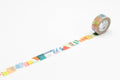 A roll of colorful patterned tape is lying on a white surface, with a pattern of geometric shapes and designs visible on the tape.