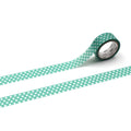 A roll of green and white polka dot tape is lying on a white surface, with the tape partially unspooled.