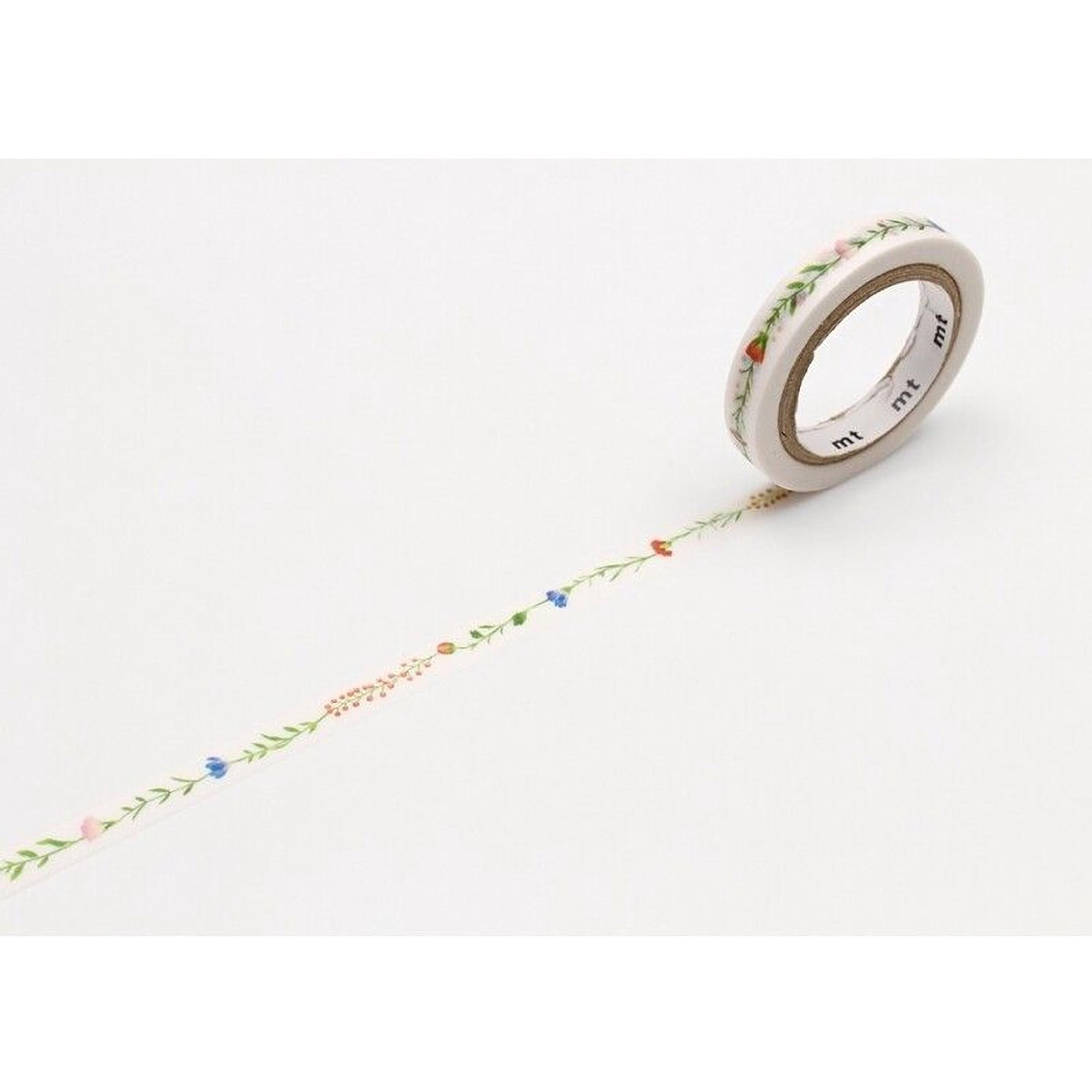 A roll of floral patterned tape is lying on a white surface, with a decorative pattern of leaves and flowers on it.