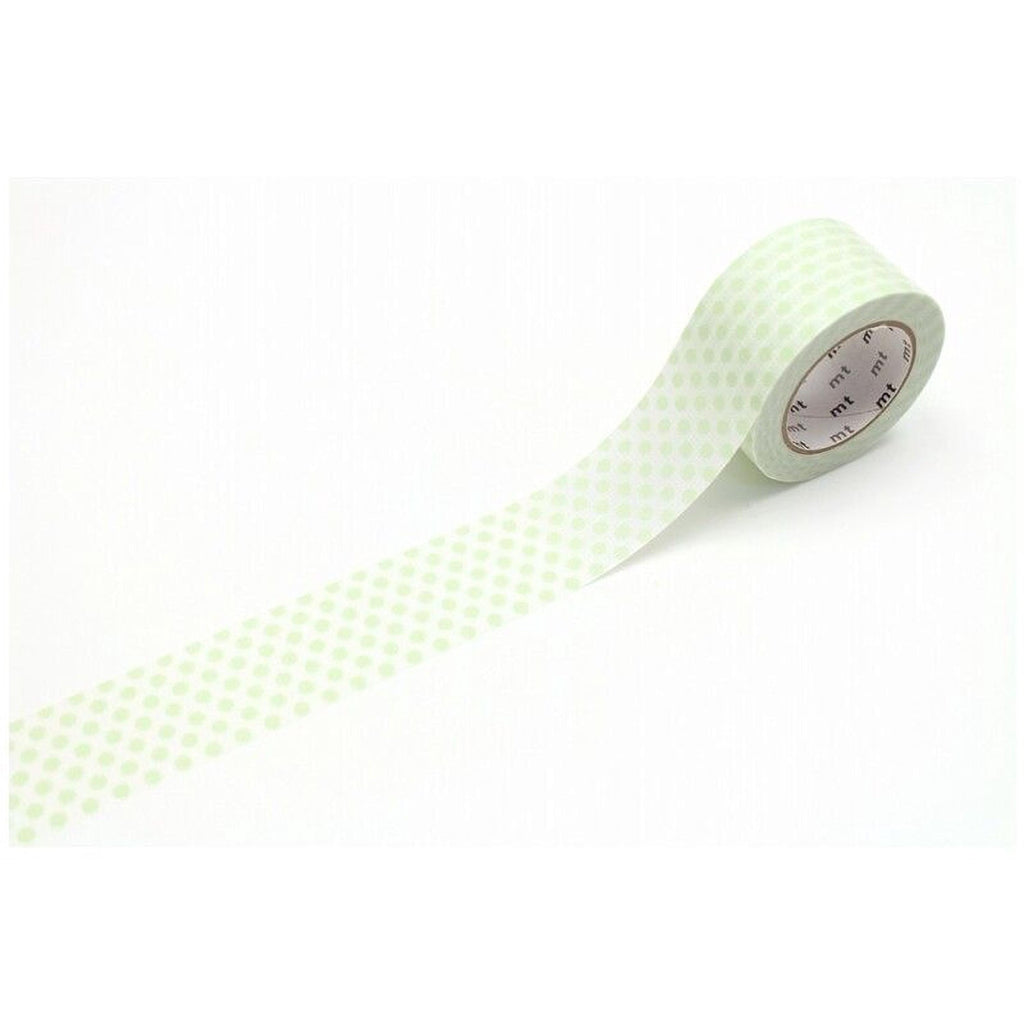 A roll of green and white polka dot tape is lying on a white surface.