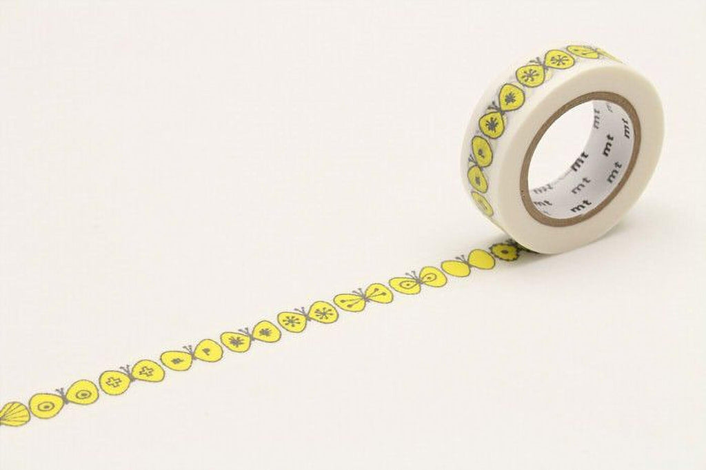 A roll of yellow and white patterned tape with a repeating design of yellow flowers and butterflies on it, lying on a white surface.