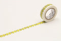 A roll of yellow and white patterned tape with a repeating design of yellow flowers and butterflies on it, lying on a white surface.