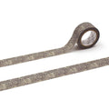 A roll of patterned tape with a floral design on it, lying on a white surface.