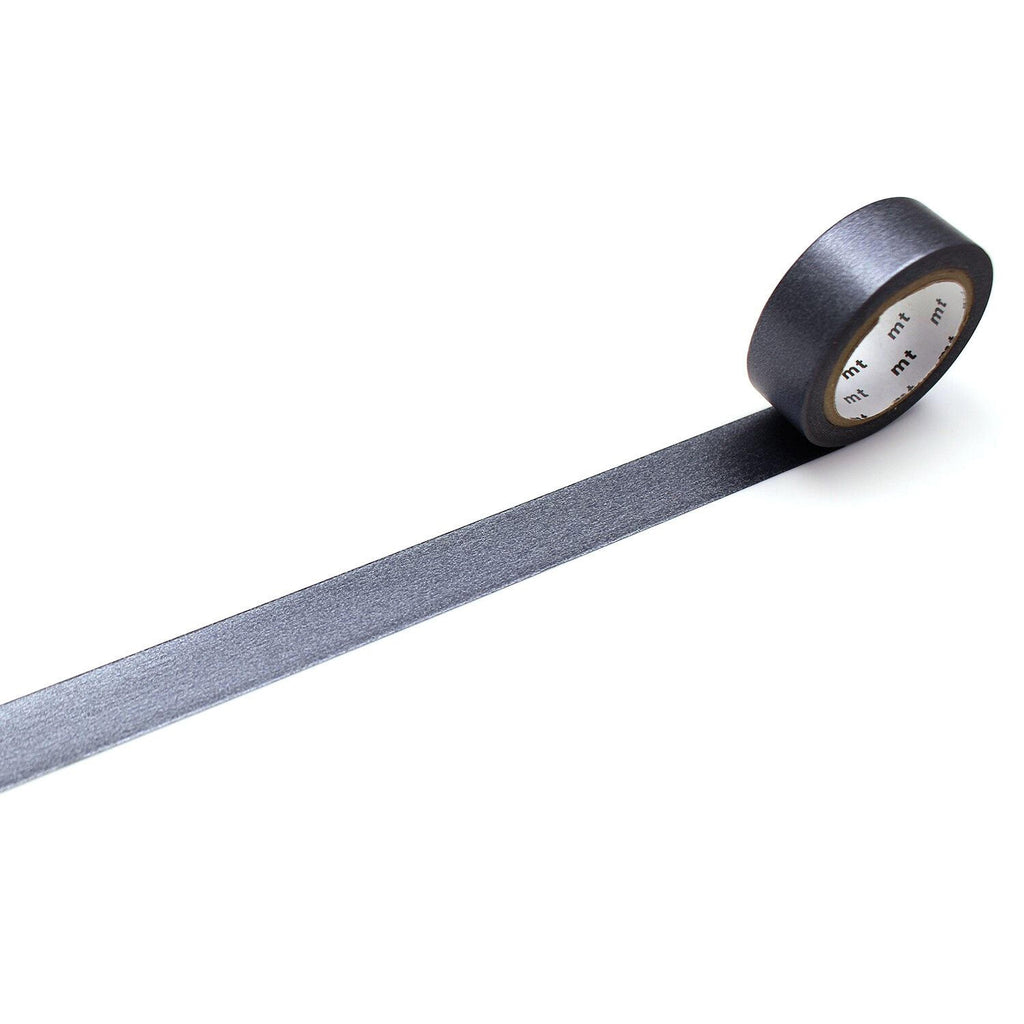 A roll of black tape with a white label is lying on a white surface, with the tape extending across the image.