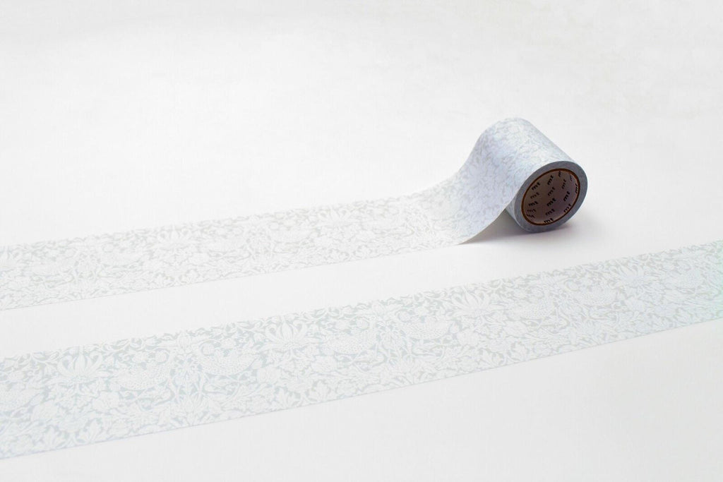 A roll of patterned tape is lying on a white surface, with a repeating pattern of white and gray designs.