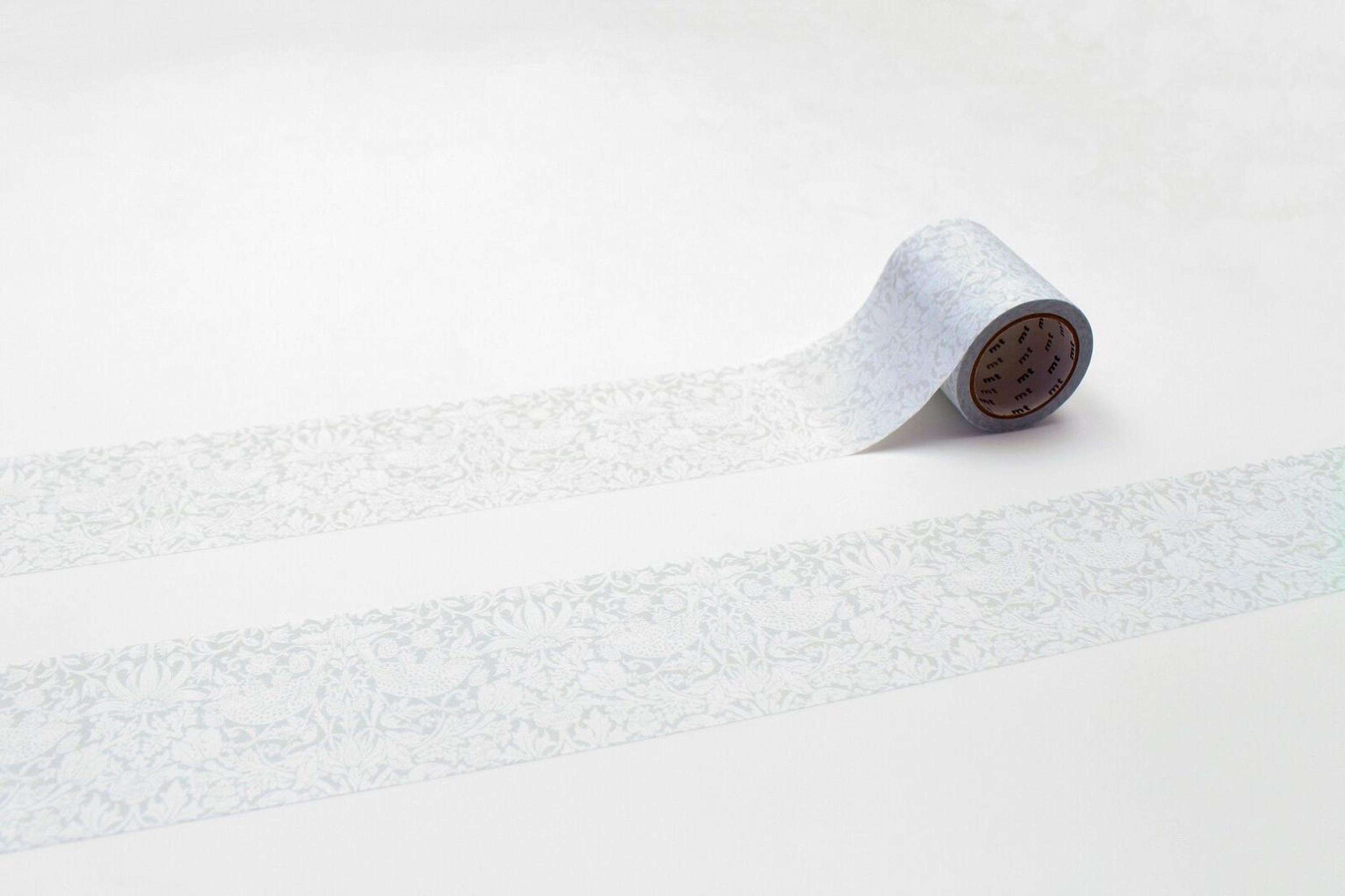 A roll of patterned tape is lying on a white surface, with a repeating pattern of white and gray designs.