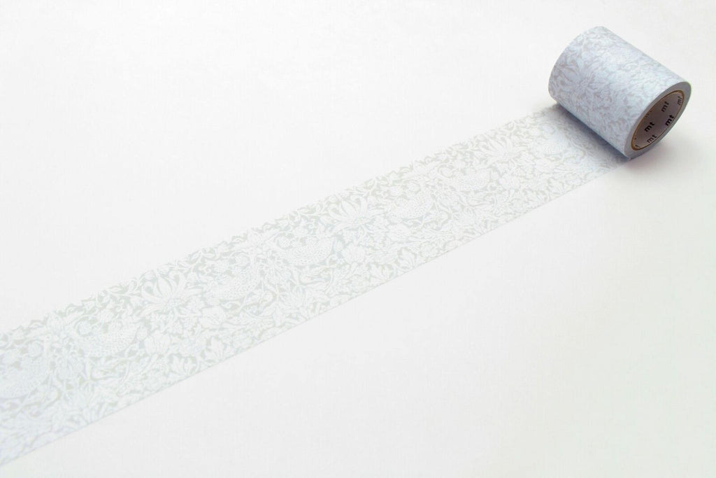 A roll of patterned tape is lying on a white surface, with a repeating floral pattern visible on the tape.