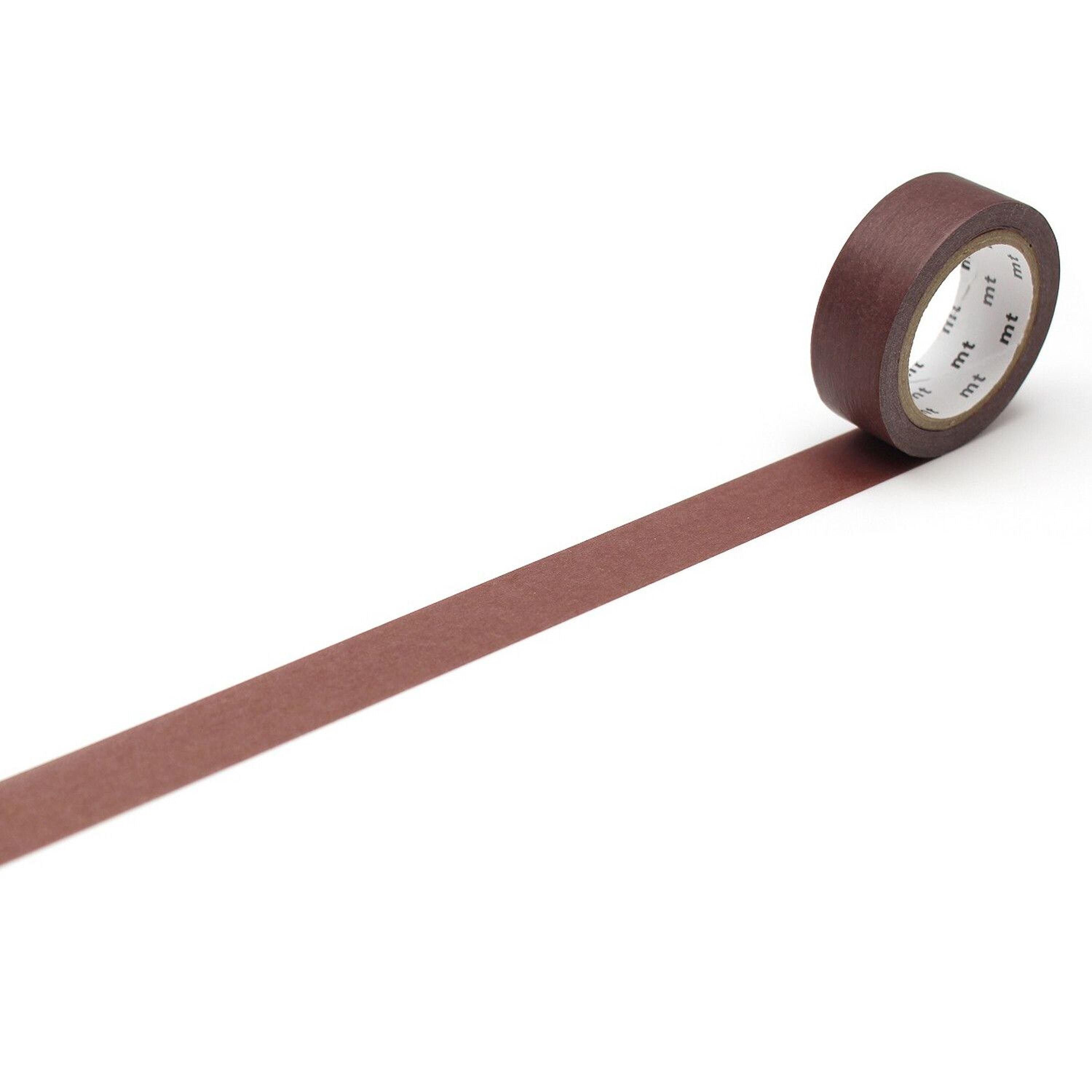 A roll of brown tape is lying on a white surface, with a single brown line extending from the tape.