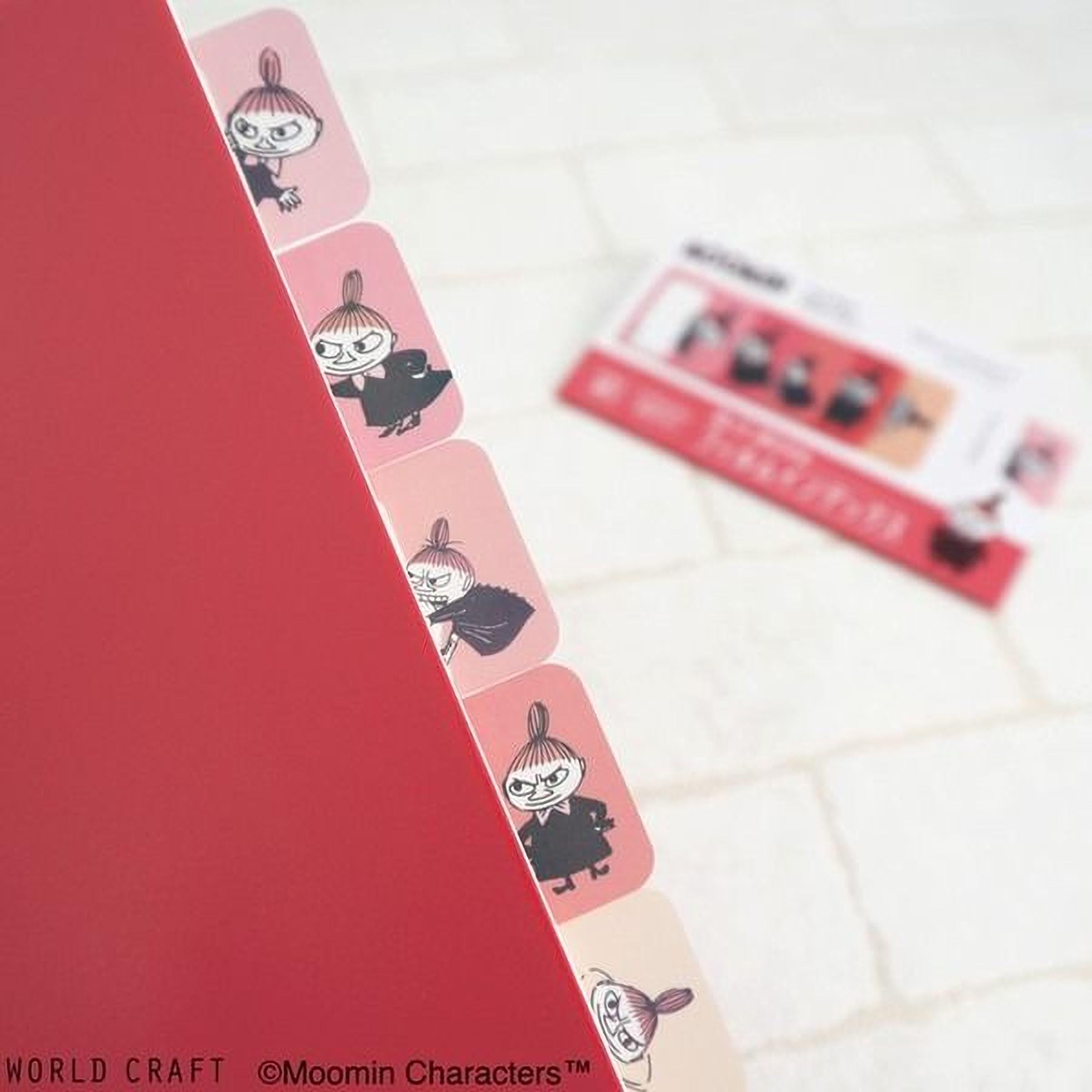 a red folder with a row of pink stickers on the left side, and a blurred background that includes a red and white ticket or card.
