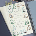 a notebook with a collection of cartoon character stickers and a list of Japanese text written in a notebook.