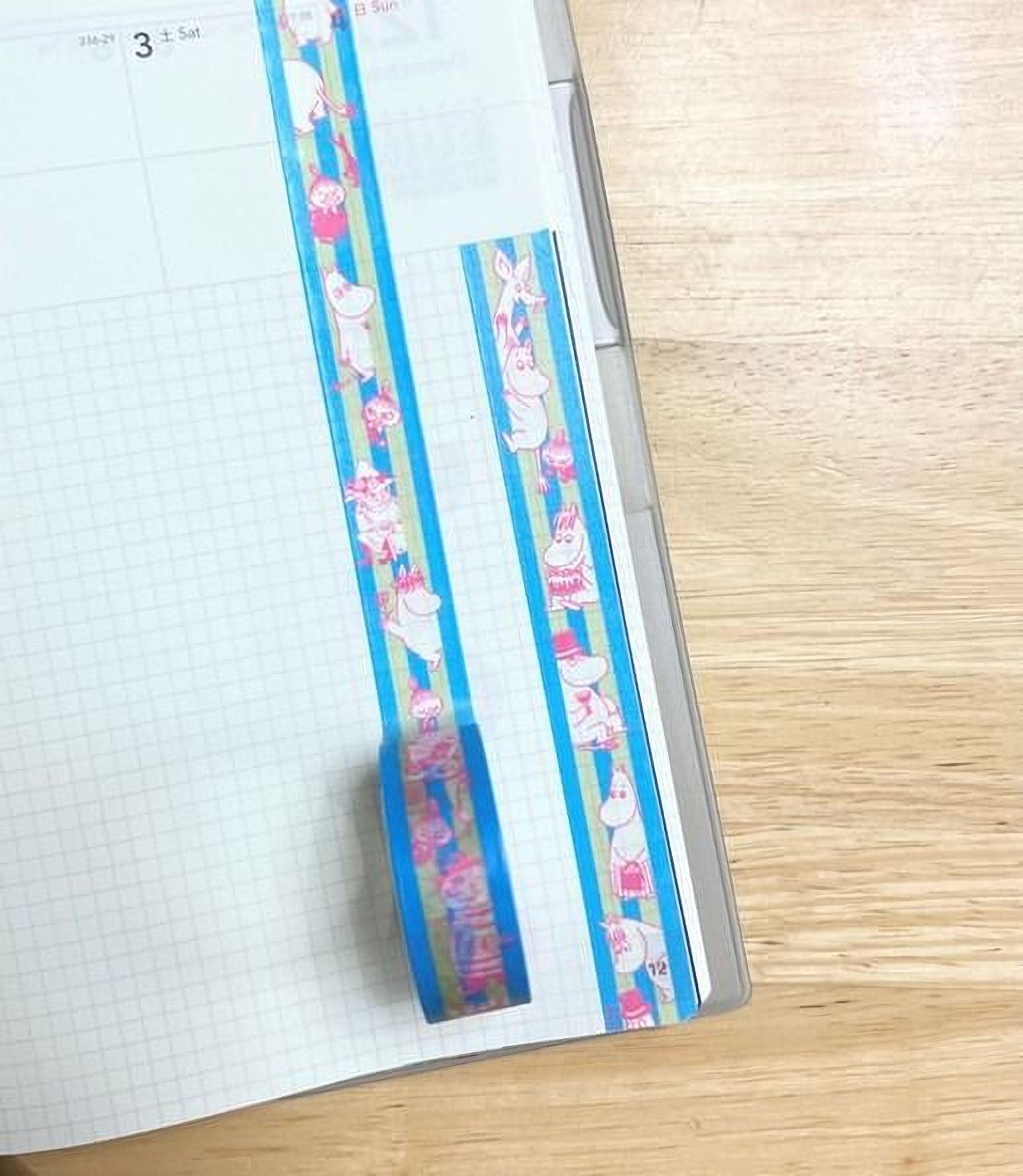 a piece of paper with a blue and pink striped tape roll placed on it, along with a grid pattern visible on the paper.