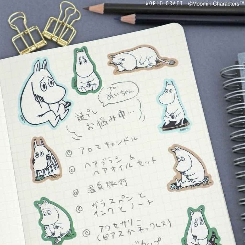a notebook with various cartoon character stickers and handwritten notes in Japanese.