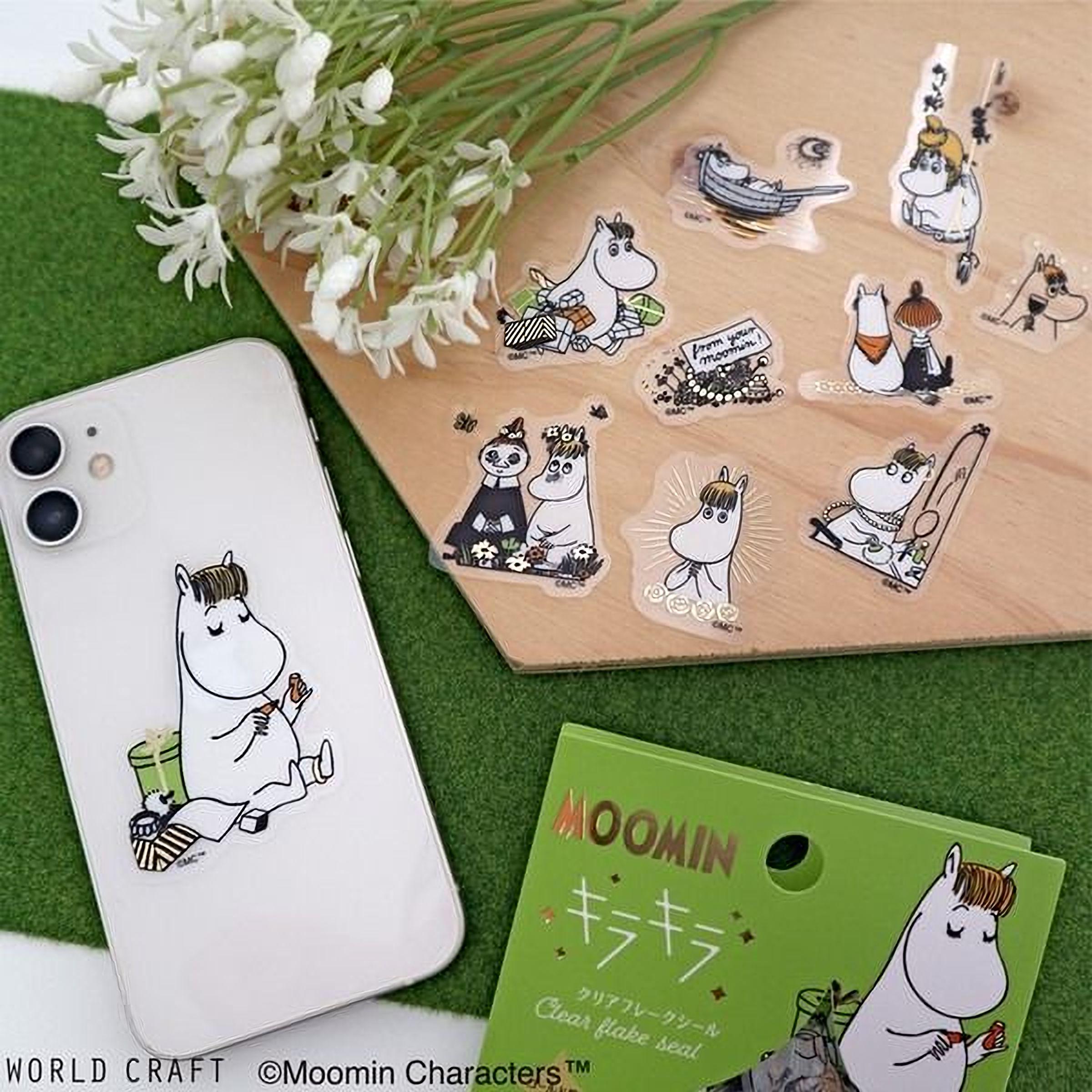 a collection of stickers and a smartphone with a floral design, all placed on a green surface.