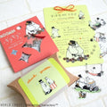 various Moomin-themed items, including a red package with a star-shaped cutout, a yellow card with illustrations of Moomin characters, and a small card with illustrations of Moomin characters.