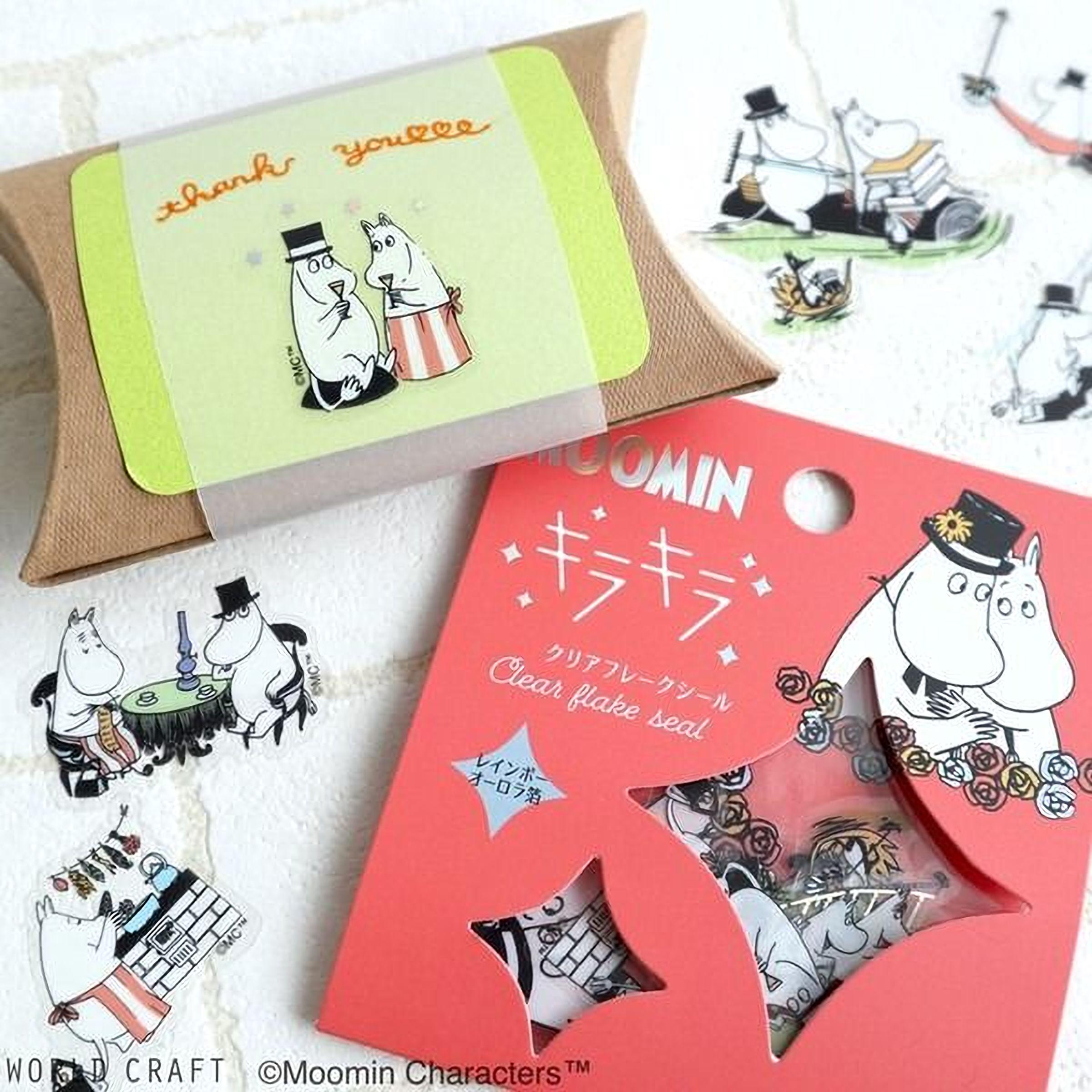 various Moomin-themed items, including a package of Moomin-themed stickers, a package of Moomin-themed paper, and a package of Moomin-themed paper with a clear plastic seal. The items are arranged on a white surface, creating a visually appealing display.