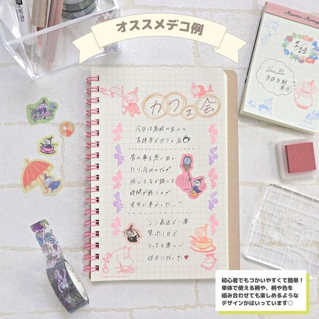 a notebook with Japanese text, a pink and white notebook, and various stationery items such as a red stamp, a clear plastic tray, and a bottle of purple and pink markers.