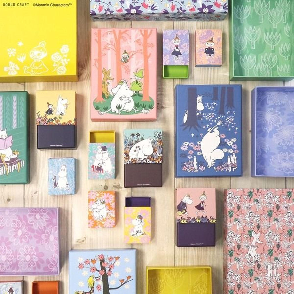 a variety of colorful boxes and containers with illustrations of Moomo characters, including a character with a hat and a character with a bow tie. The boxes are arranged in a grid-like pattern on a wooden surface, showcasing the diverse designs and themes of the Moomo characters.
