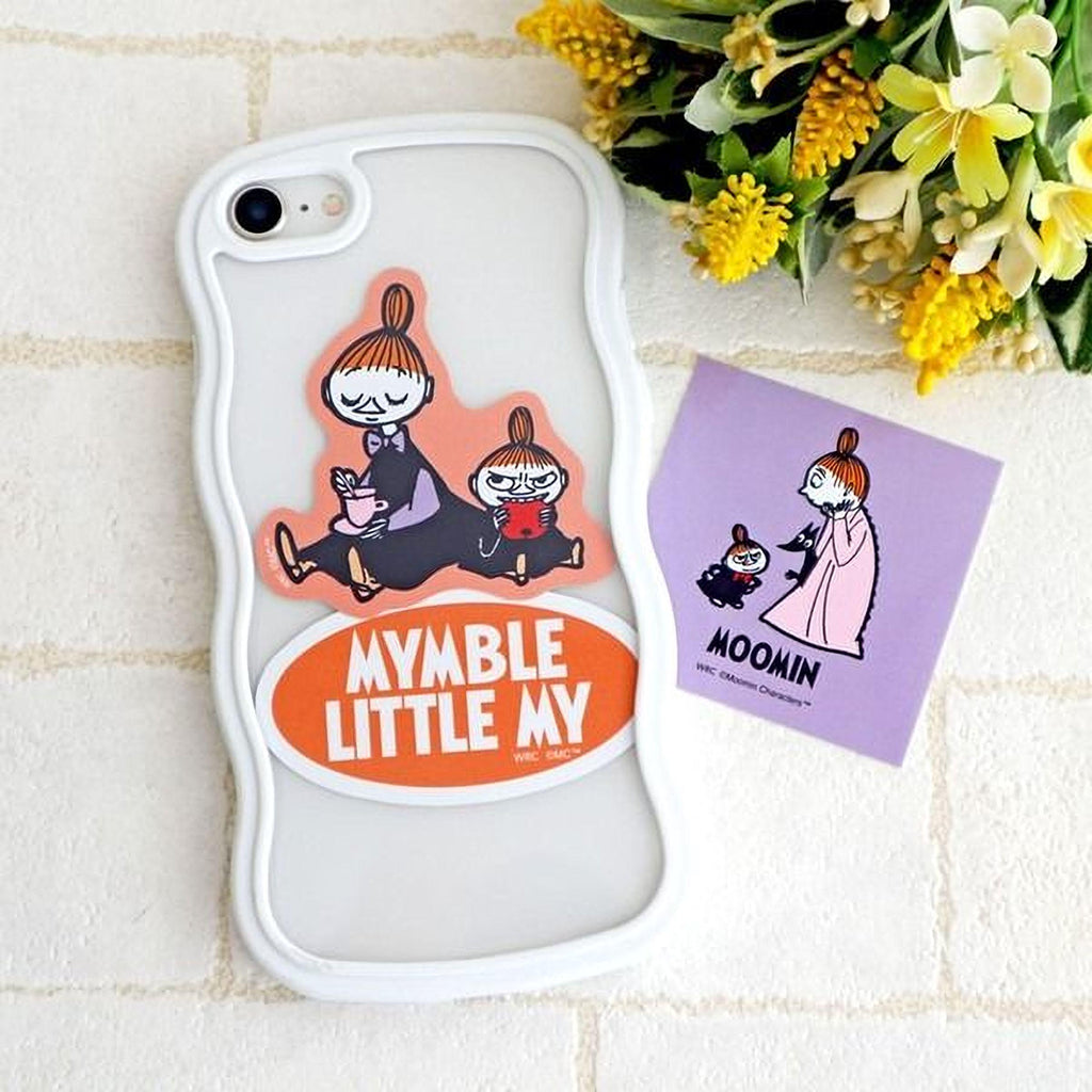 a white phone case with a sticker of a cartoon character and a purple sticker with a cartoon character. There is also a bouquet of yellow flowers in the background.