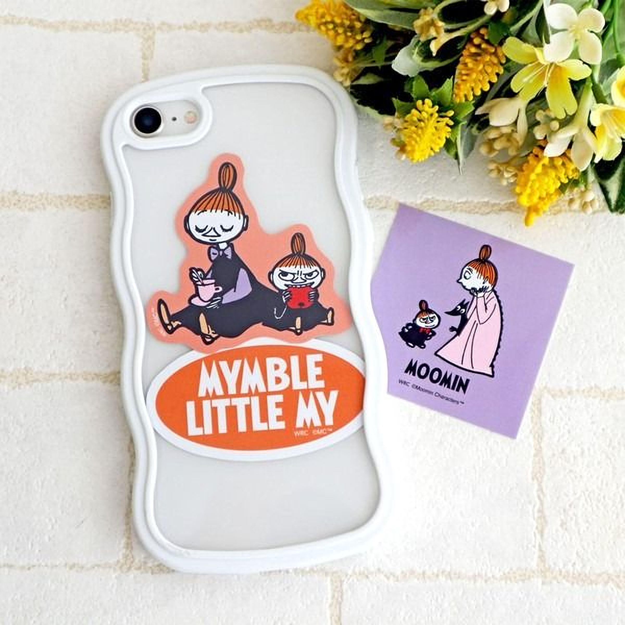 a white phone case with a sticker of a cartoon character and a purple sticker with a cartoon character. There is also a bouquet of yellow flowers in the background.