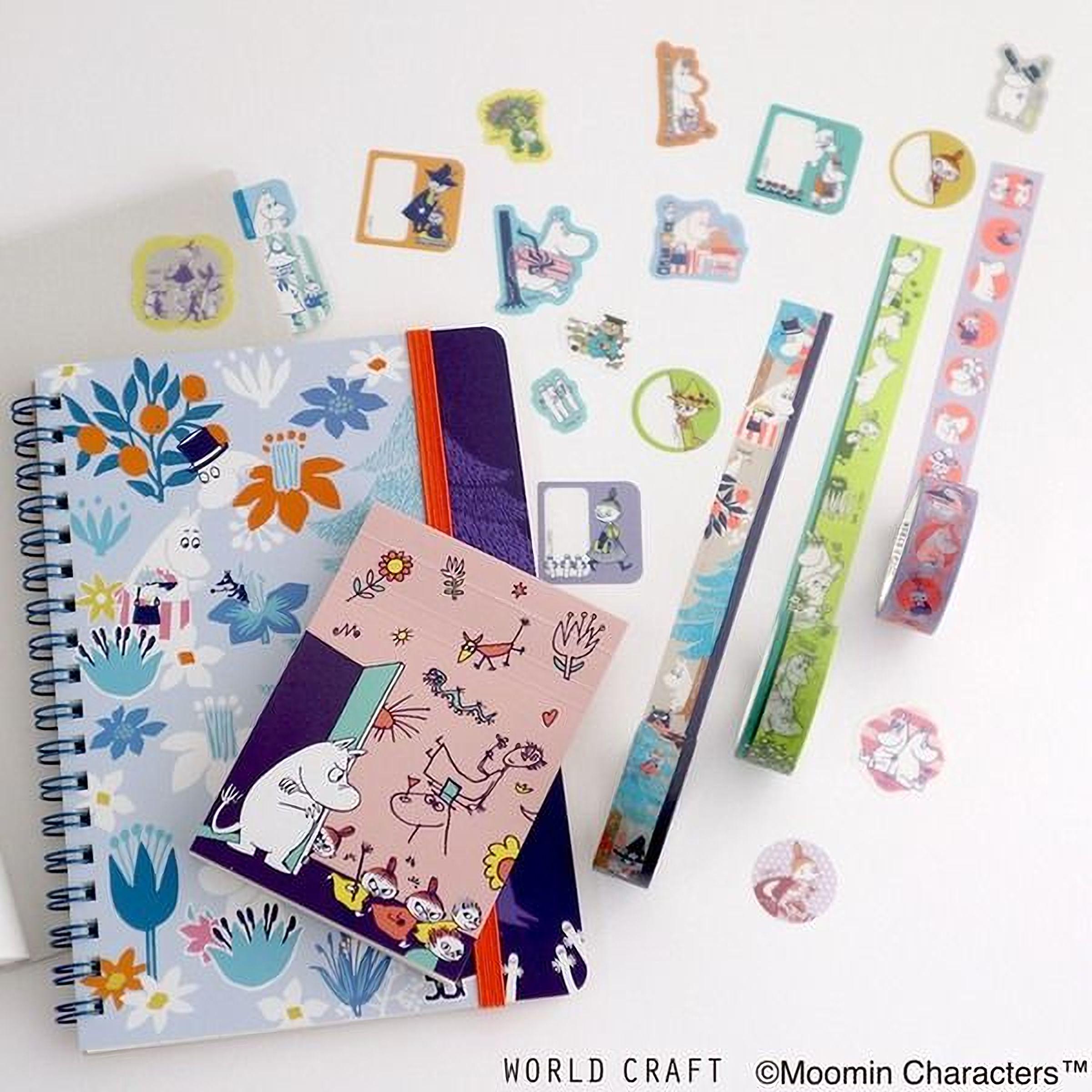 various colorful items, including a notebook, stickers, and a pen, arranged on a white surface.