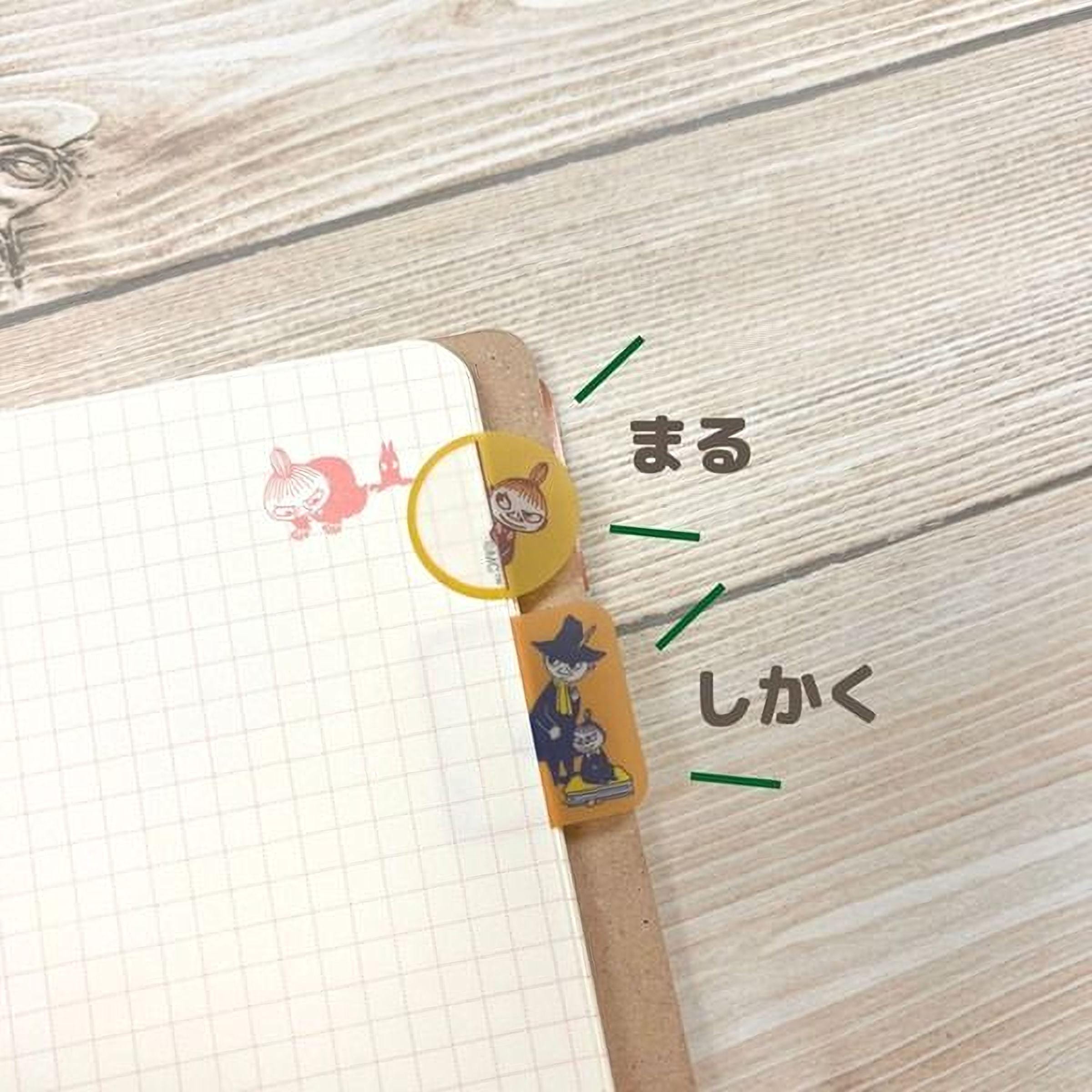 a notebook with a grid pattern, a yellow and orange bookmark, and some Japanese text.
