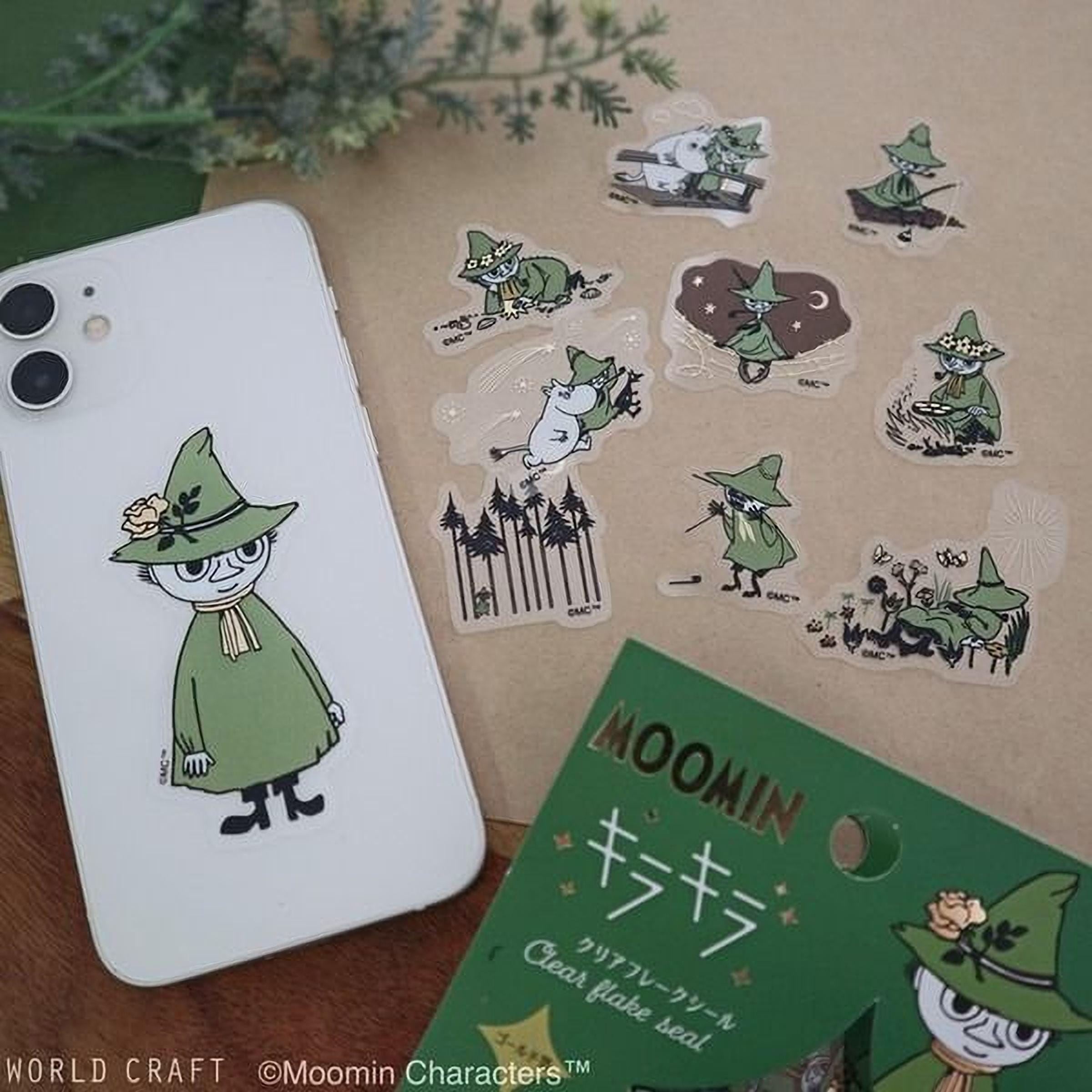 a white smartphone with a green sticker depicting a character from the Moomin cartoon series, along with several other stickers of the same character in various poses.